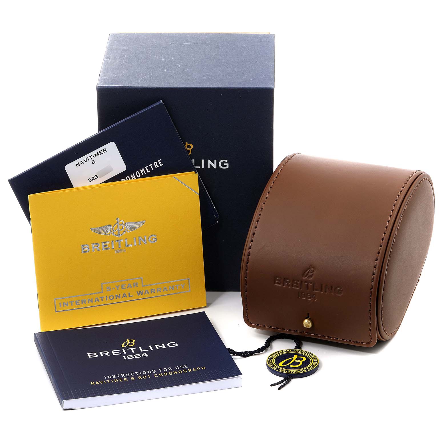 The image shows the Breitling Navitimer model’s accessories, including the box, warranty card, instruction manual, and a brown watch case.