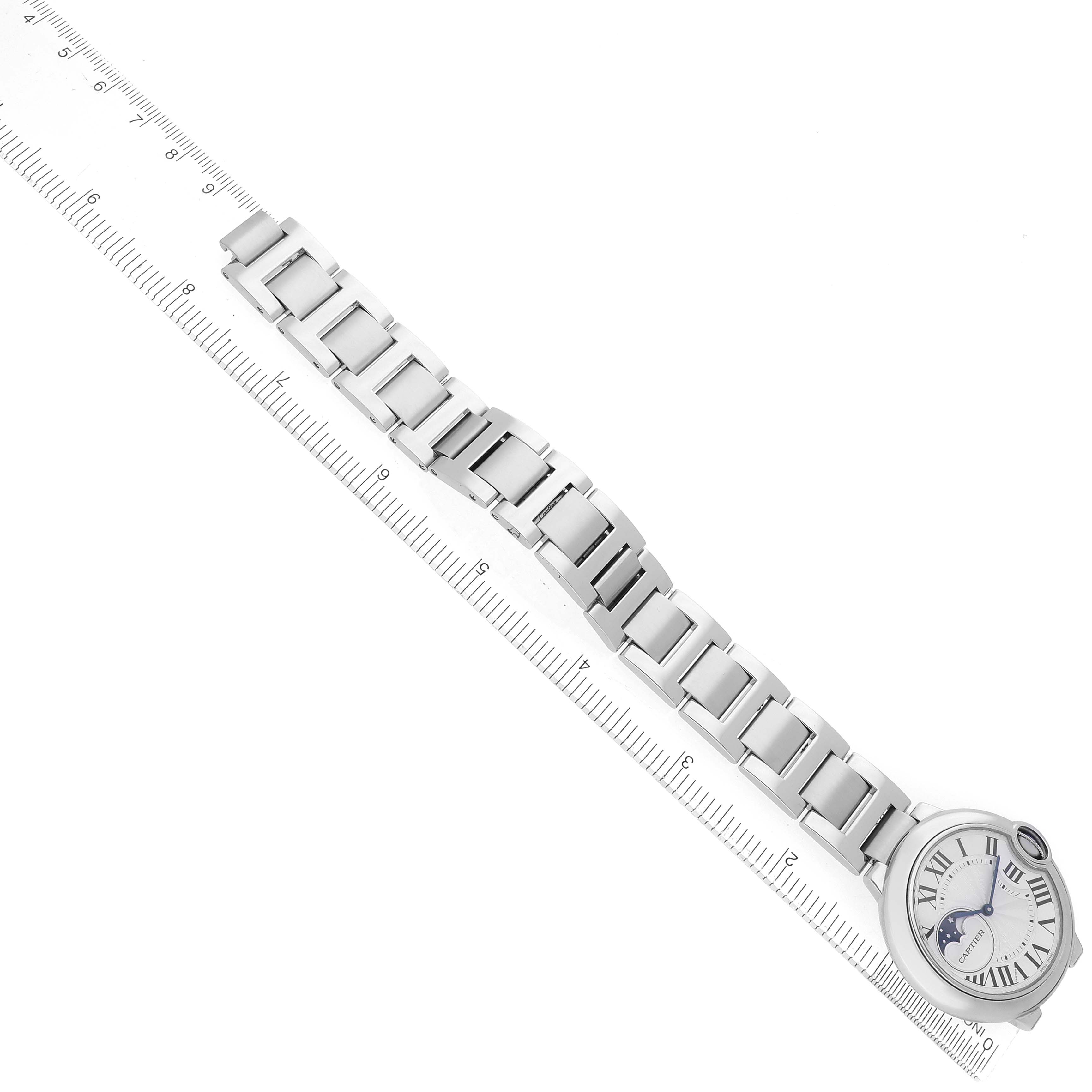 The Cartier Ballon Bleu WSBB0021 Men's Stainless Steel Silver Dial watch is shown from above with a focus on its bracelet and face alongside a ruler for scale.
