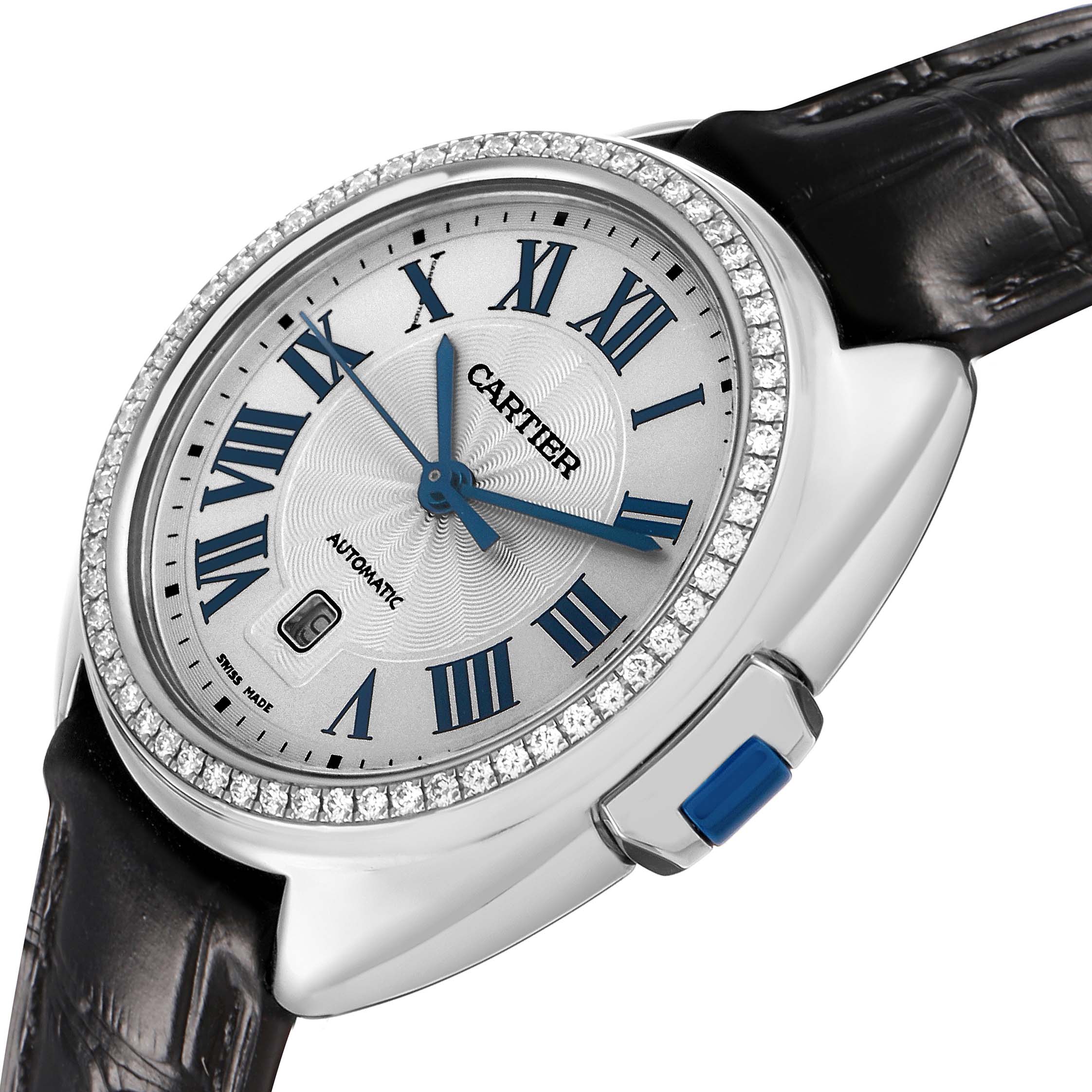 The Cartier Clé watch is shown at an angled close-up, highlighting its diamond bezel, Roman numeral dial, and blue hands.