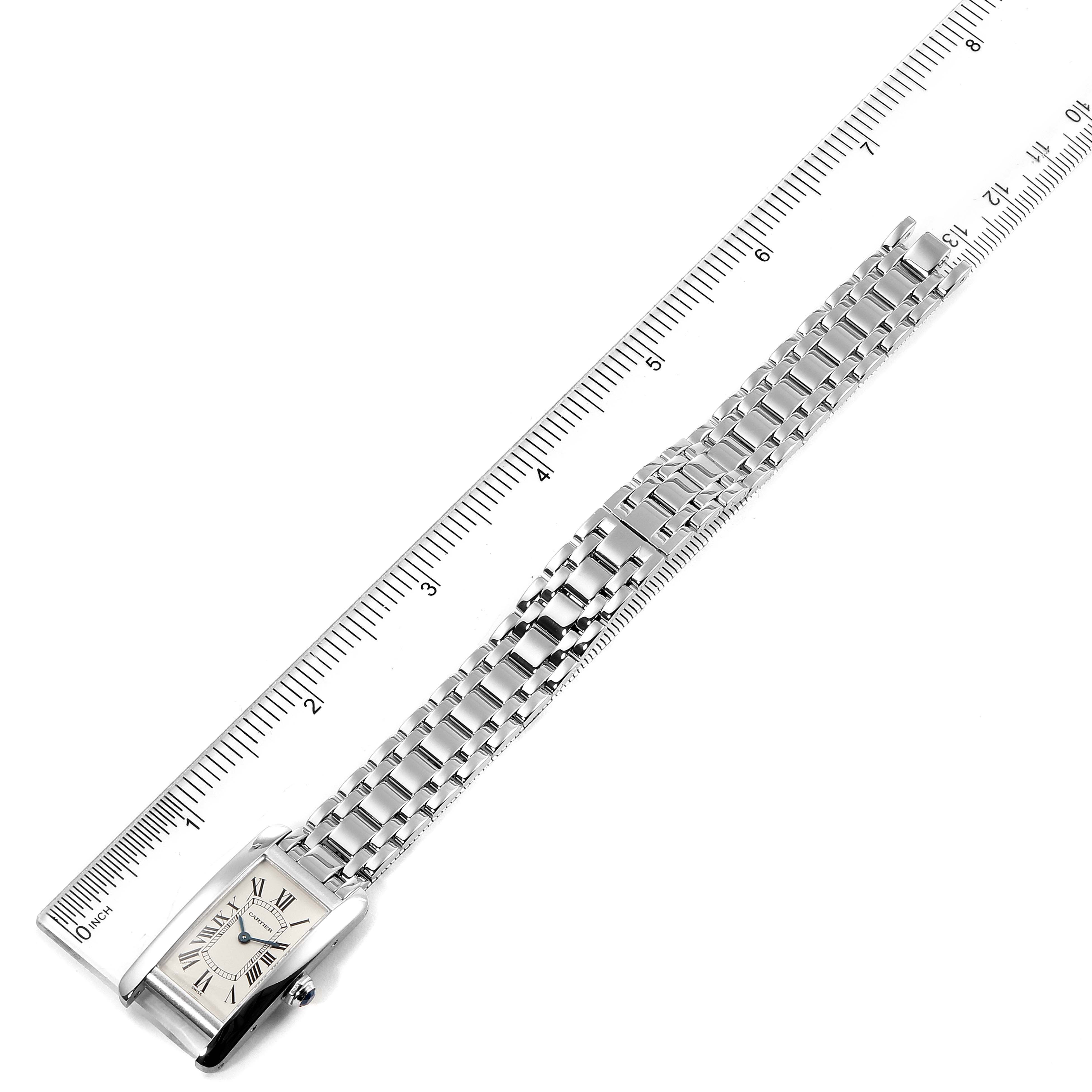 The image shows a Cartier Tank Americaine W26019L1  Women's White Gold Silver Dial W26019L1  Women's White Gold Silver Dial watch, featuring a full view of the watch face and bracelet, laid flat beside a ruler.