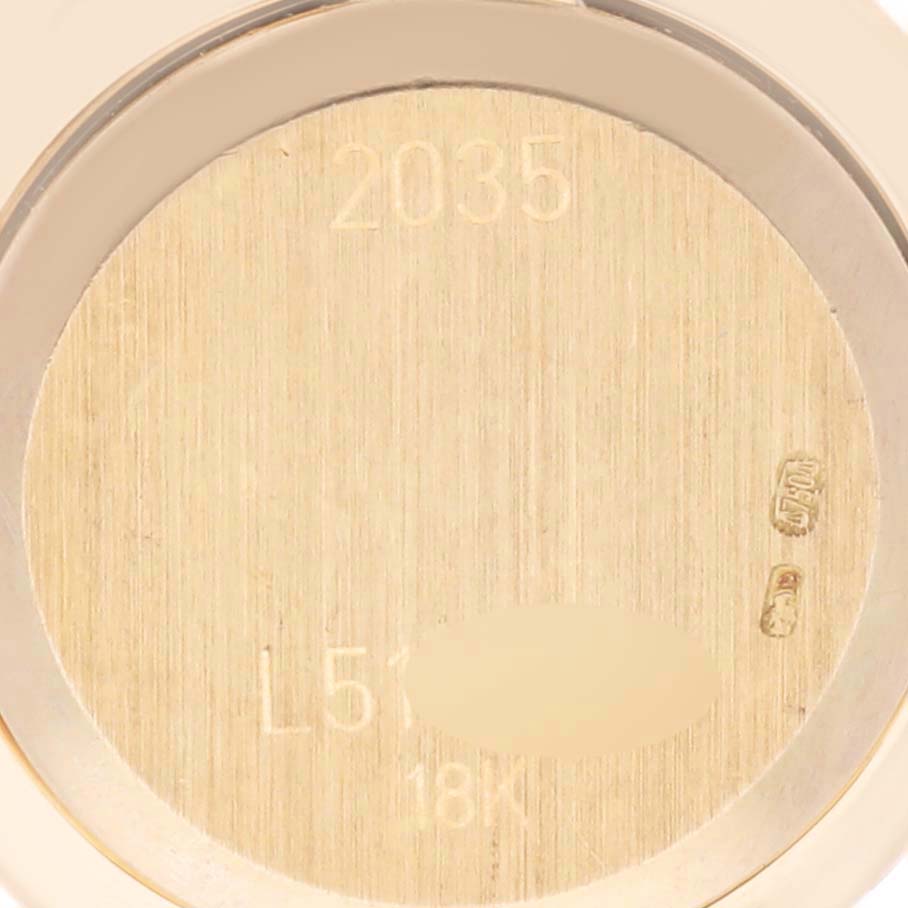 This is a close-up view of the back case interior of a Rolex Cellini 2035 Women
s Yellow Gold Mother of Pearl Dial 2035 Women
s Yellow Gold Mother of Pearl Dial watch, showing engravings and metal markings.