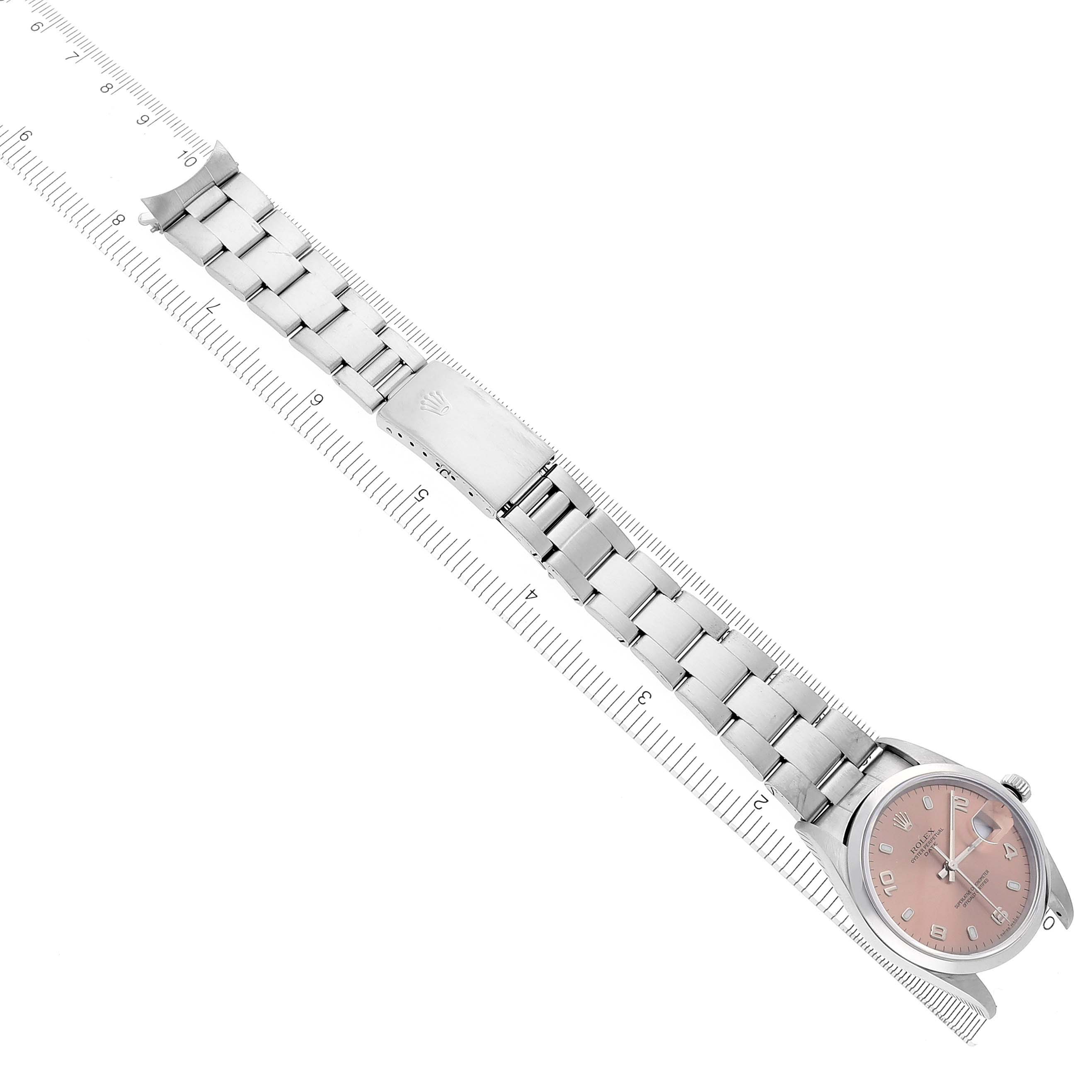 The Rolex Date 15200 Men's Stainless Steel Pink Dial 15200 Men's Stainless Steel Pink Dial watch is shown from a top angle, highlighting the face, bracelet, and clasp alongside a ruler for scale.