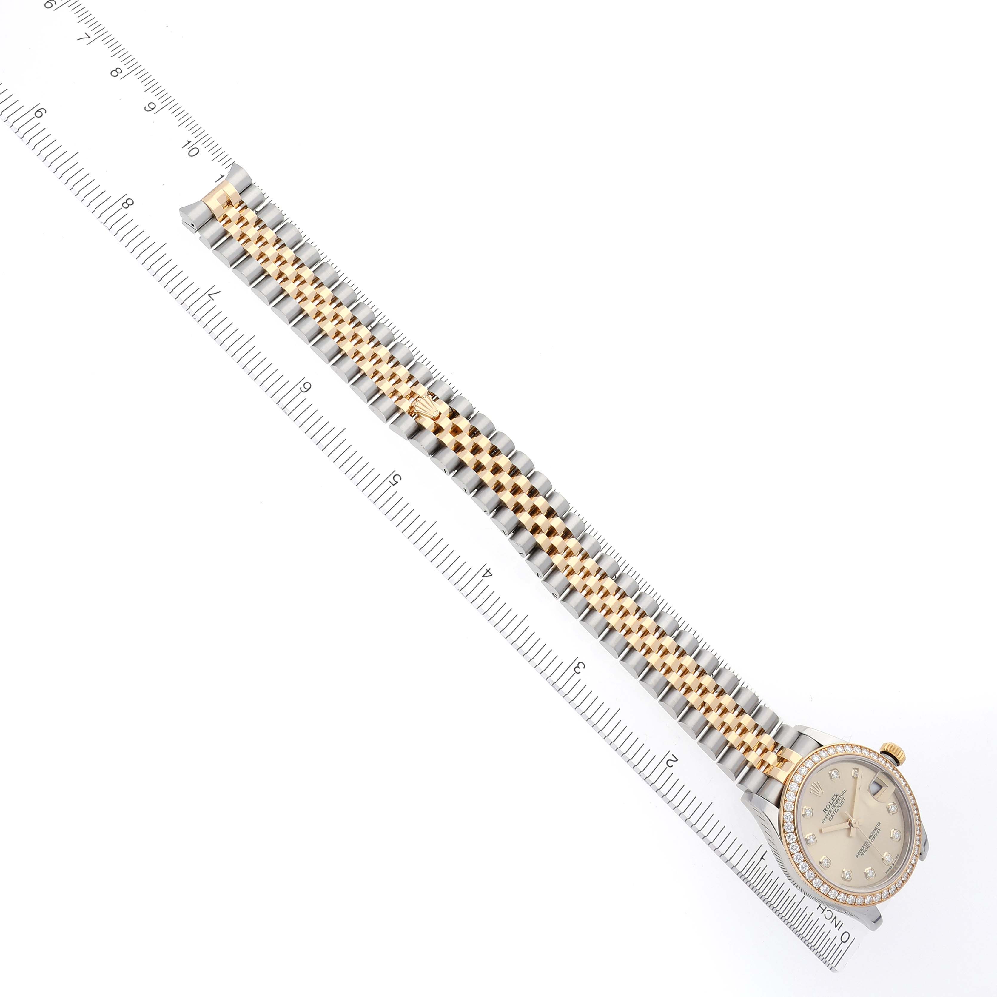 The Rolex Mid-Size 278383RBR Women's Steel and Gold (two tone) Champagne Dial 278383RBR Women's Steel and Gold (two tone) Champagne Dial watch is shown from a top-down angle, displaying its bracelet and face beside a ruler.