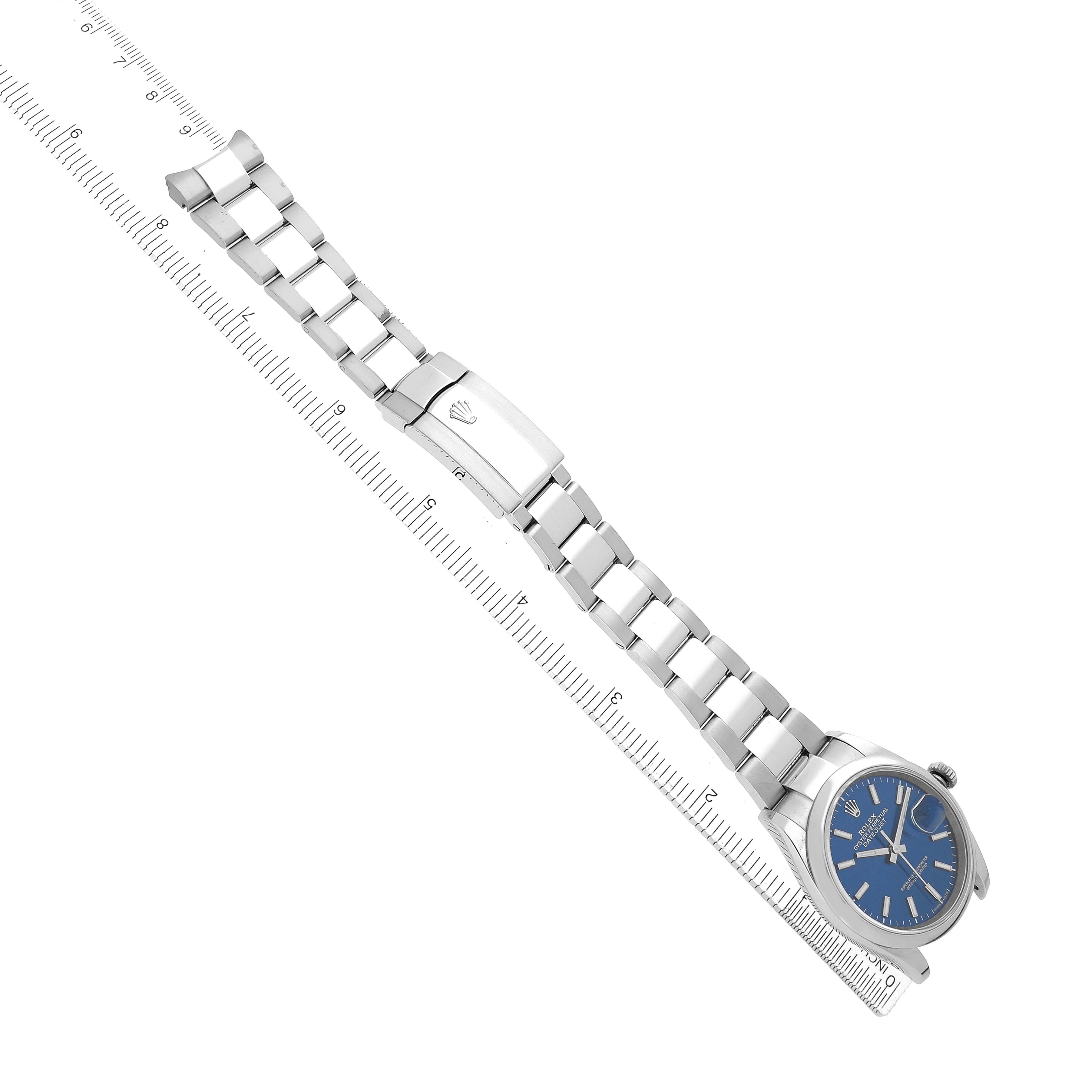 The image shows a Rolex Datejust 126200 Men's Stainless Steel Blue Dial watch from an angled top-down view, highlighting the face and bracelet alongside a ruler for scale.