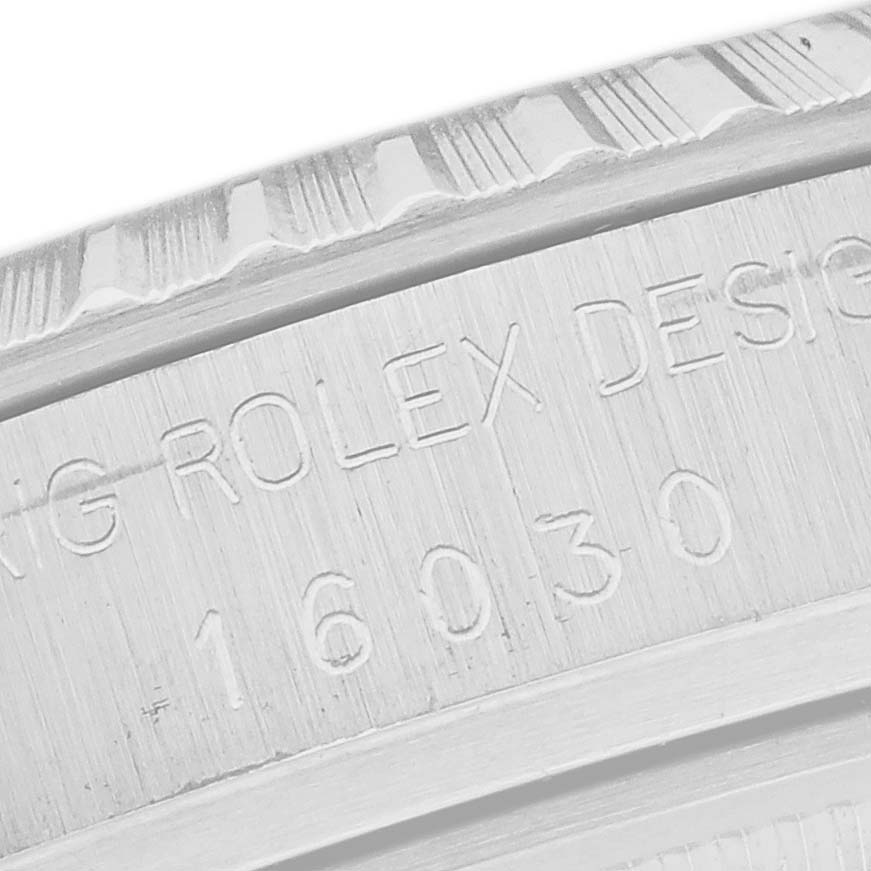 The image shows the side of a Rolex Datejust 16030 Men
s Stainless Steel Silver Dial 16030 Men
s Stainless Steel Silver Dial case with engraved text detailing the model number.