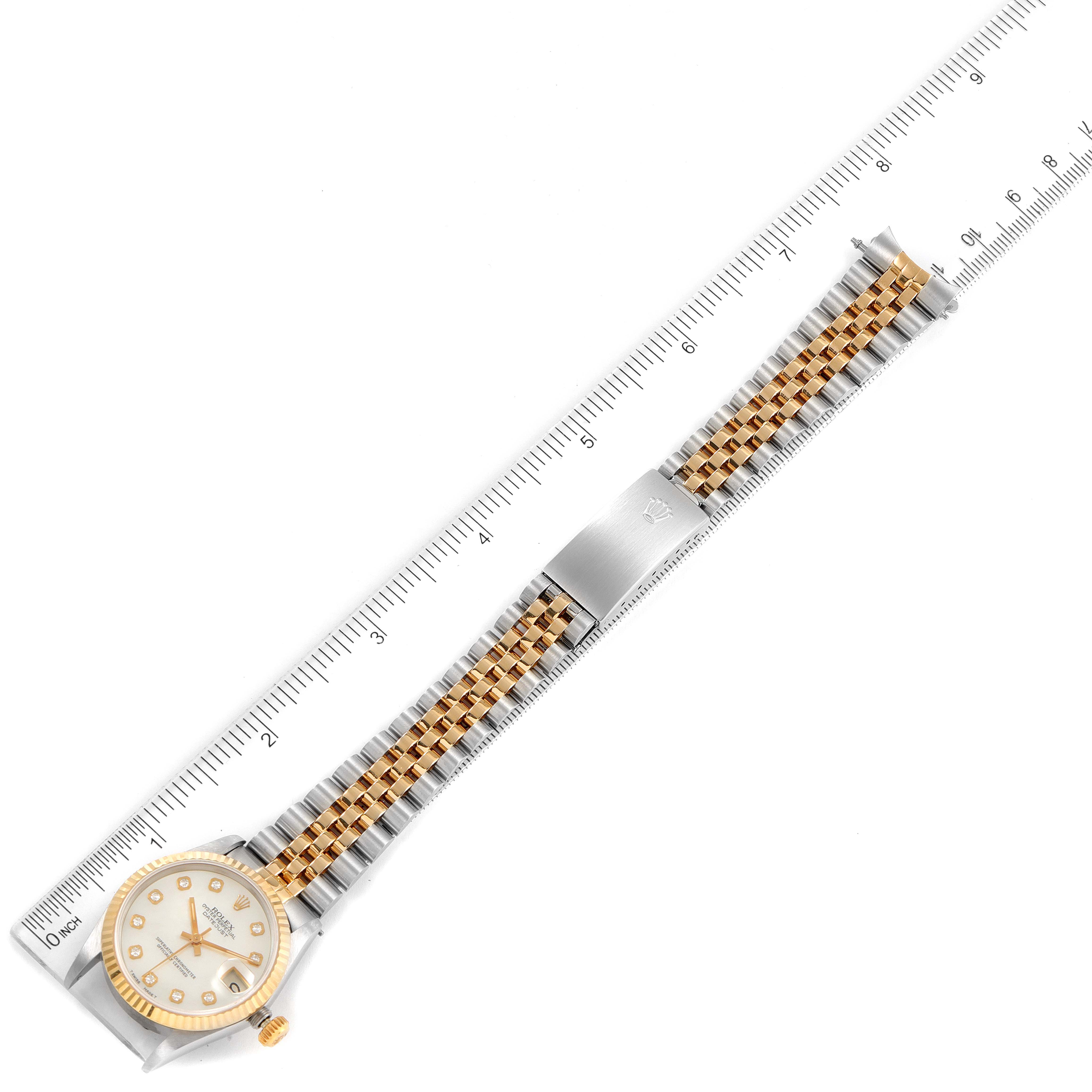 The image shows a top-down view of a Rolex Mid-Size 68273 Women's Steel and Gold (two tone) Mother of Pearl Dial 68273 Women's Steel and Gold (two tone) Mother of Pearl Dial model watch with its face, bezel, and two-tone bracelet placed against a ruler.