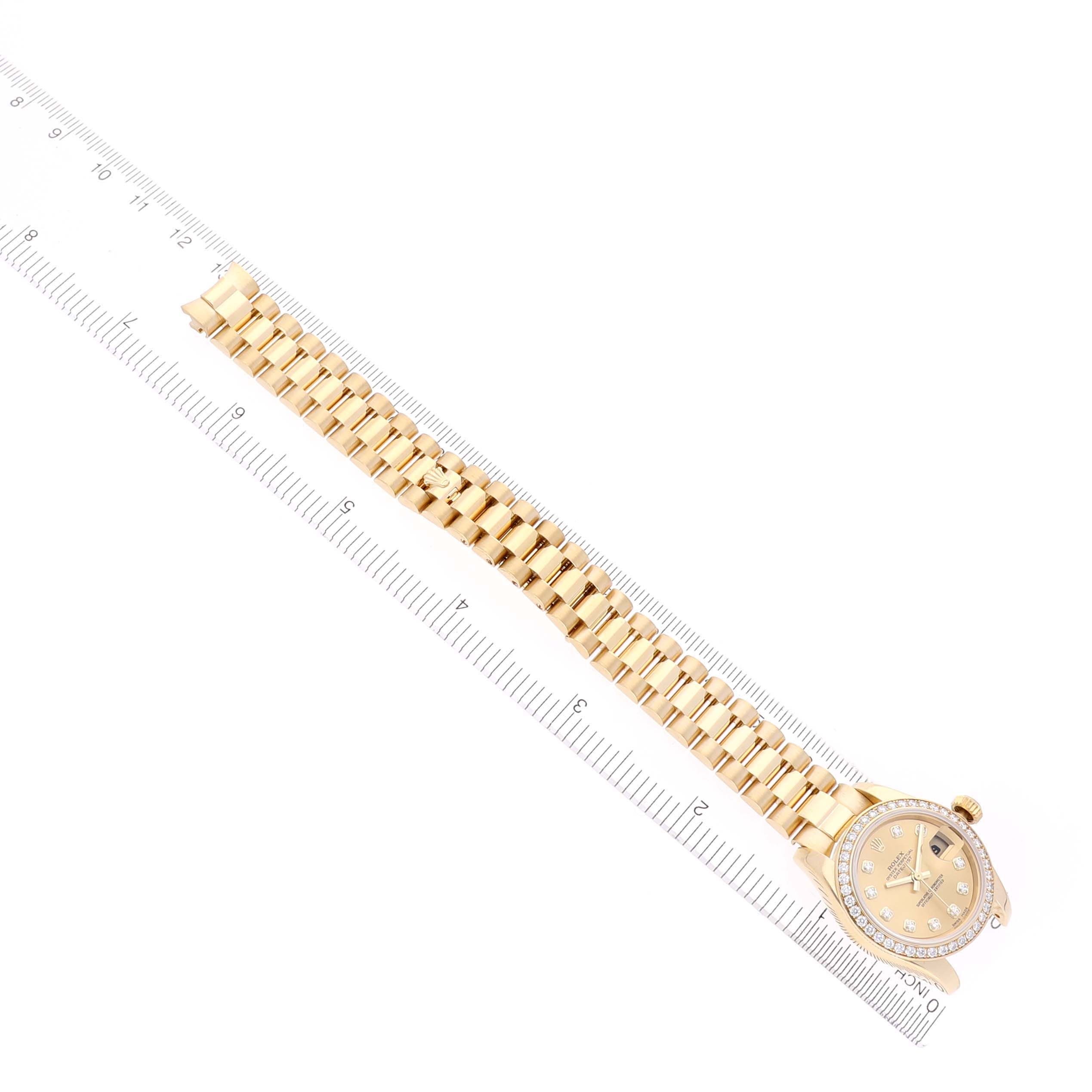 The Rolex President 179138 Women's Yellow Gold Champagne Dial 179138 Women's Yellow Gold Champagne Dial watch is shown from a top-down angle, displaying the full bracelet and face with a ruler for scale.