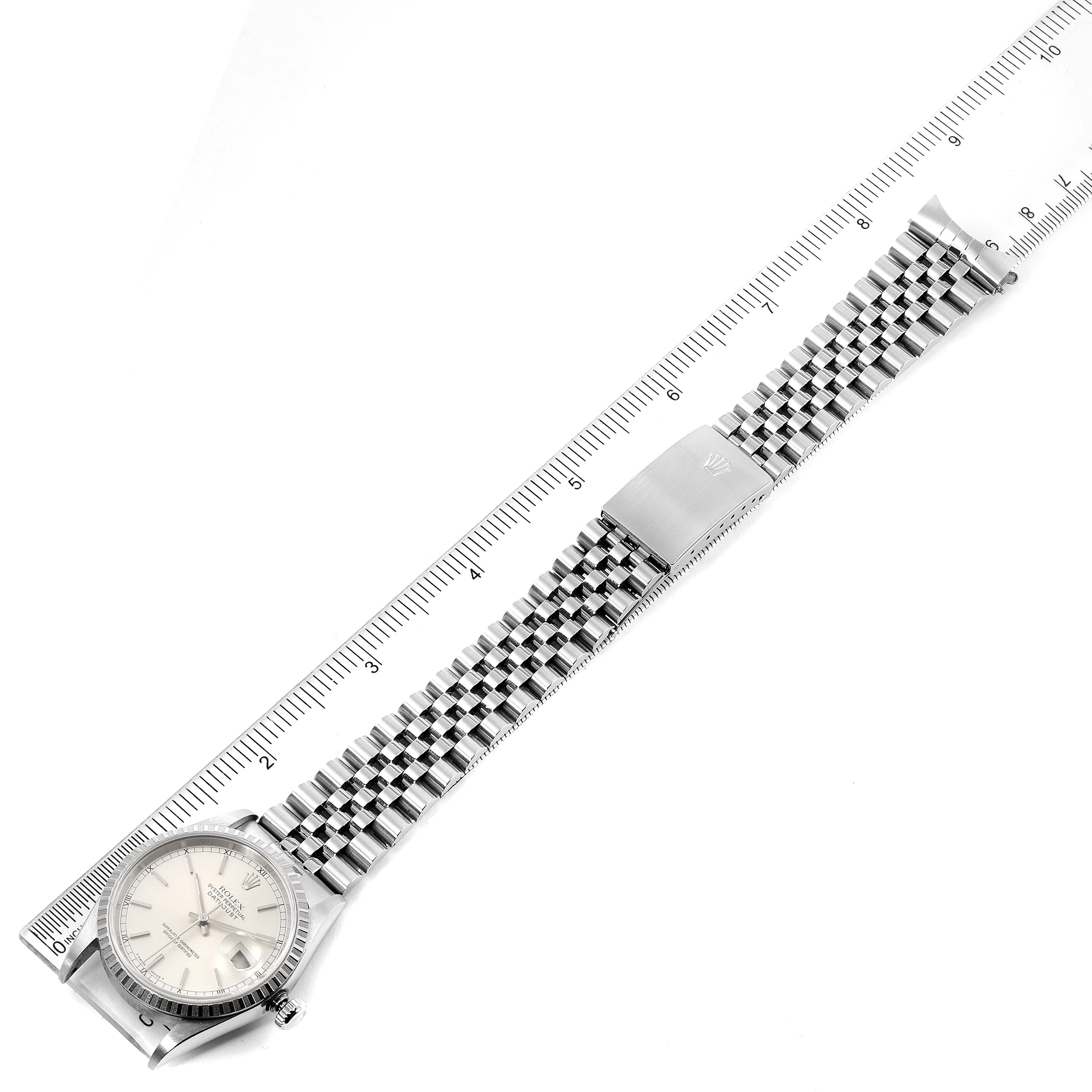The image shows a top-down view of a Rolex Datejust 16220 Men's Stainless Steel Silver Dial 16220 Men's Stainless Steel Silver Dial watch, displaying the dial, bezel, and bracelet against a ruler.