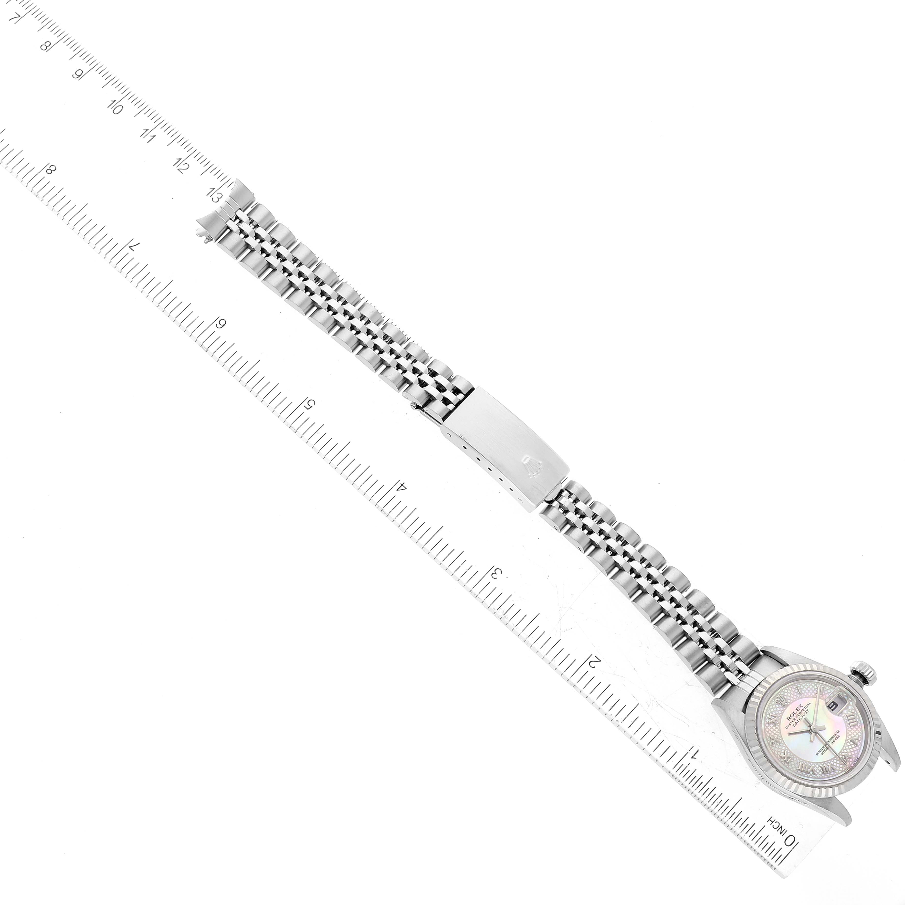 The Rolex Datejust 79174 Women's Stainless Steel Mother of Pearl Dial 79174 Women's Stainless Steel Mother of Pearl Dial watch is shown from an overhead angle with a ruler alongside its strap for scale.