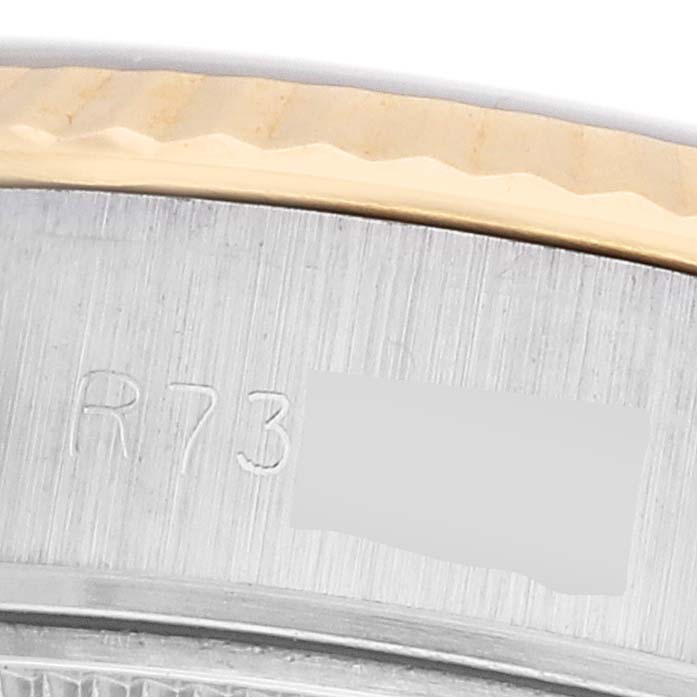 The image shows a close-up of the Rolex Datejust 69173 Women's Steel and Gold (two tone) Silver Dial's bezel and engraved serial number on the case side.