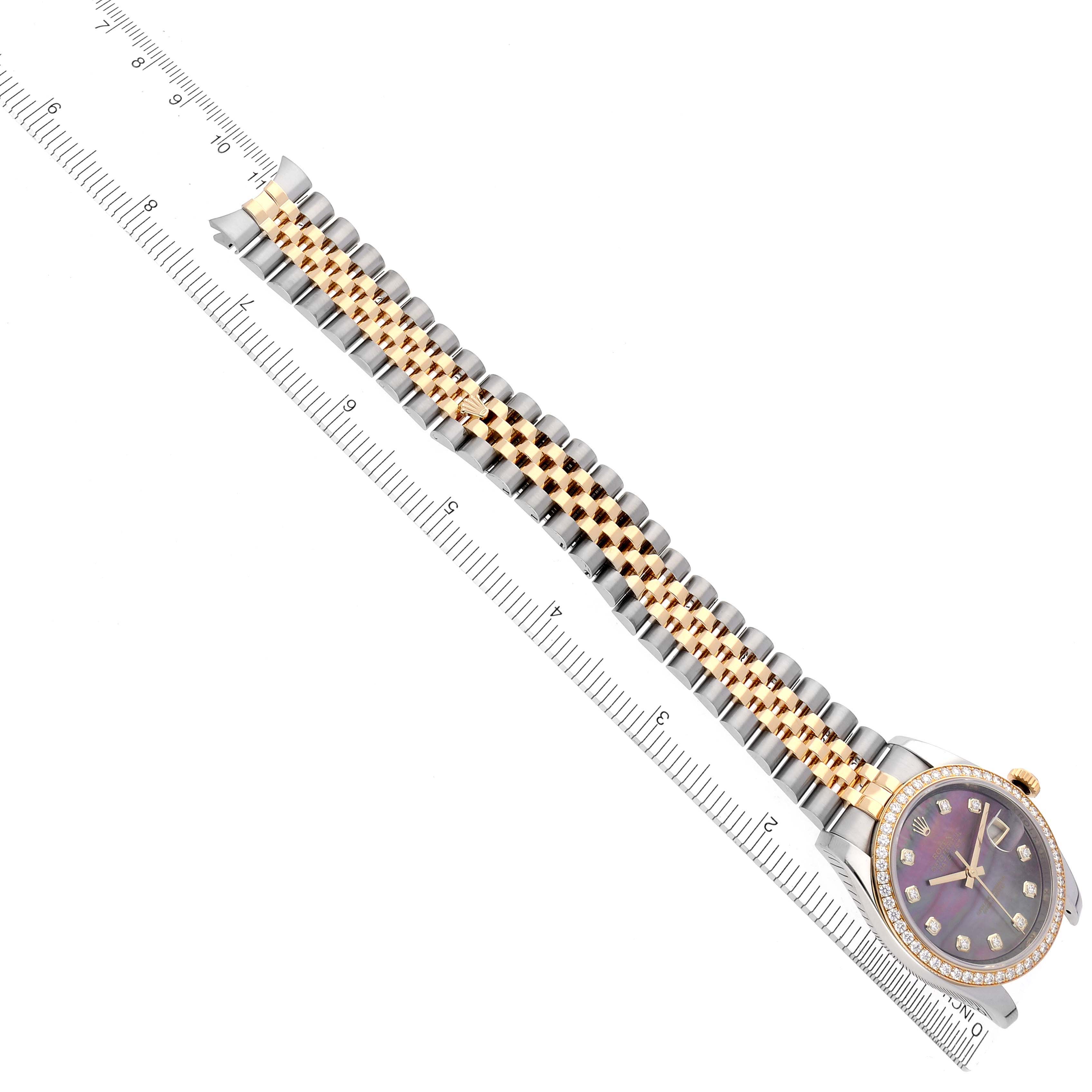 The Rolex Datejust 116243 Men's Steel and Gold (two tone) Mother of Pearl Dial 116243 Men's Steel and Gold (two tone) Mother of Pearl Dial watch is shown at an overhead angle, displaying its face, bezel, and full bracelet alongside a ruler.