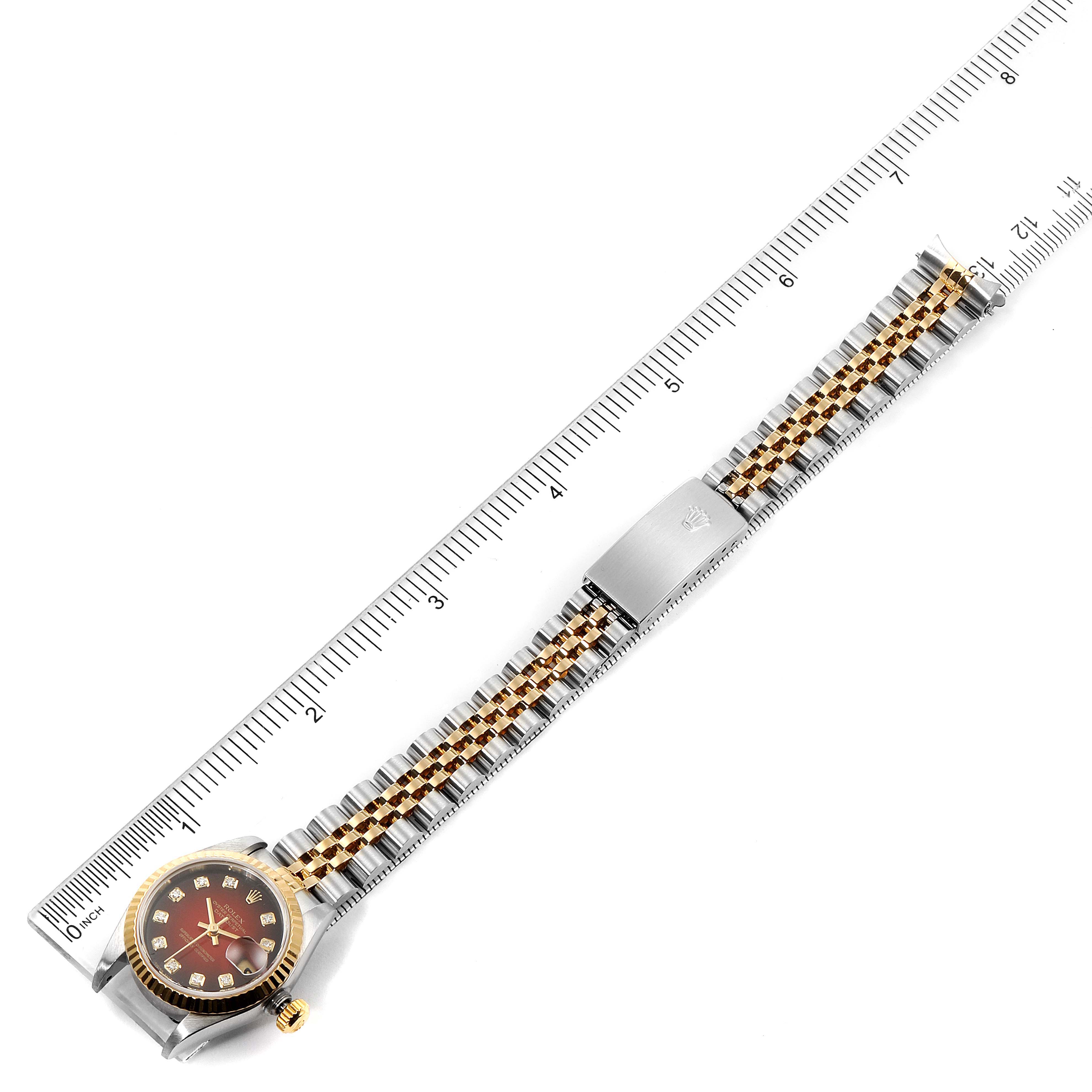 The Rolex Datejust 79173 Women's Steel and Gold (two tone) Red Dial 79173 Women's Steel and Gold (two tone) Red Dial watch is shown from a top-down angle, displaying the entire watch, strap, and clasp beside a ruler.