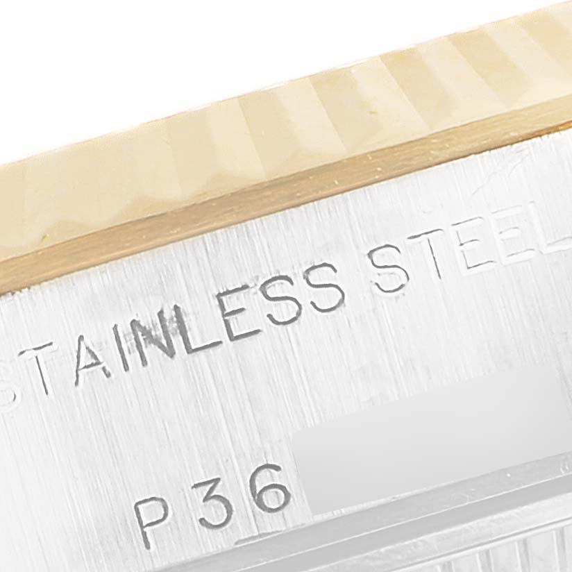 This close-up image shows the stainless steel etching and part of the fluted bezel of a Rolex Datejust 79173 Women's Steel and Gold (two tone) Red Dial 79173 Women's Steel and Gold (two tone) Red Dial model.