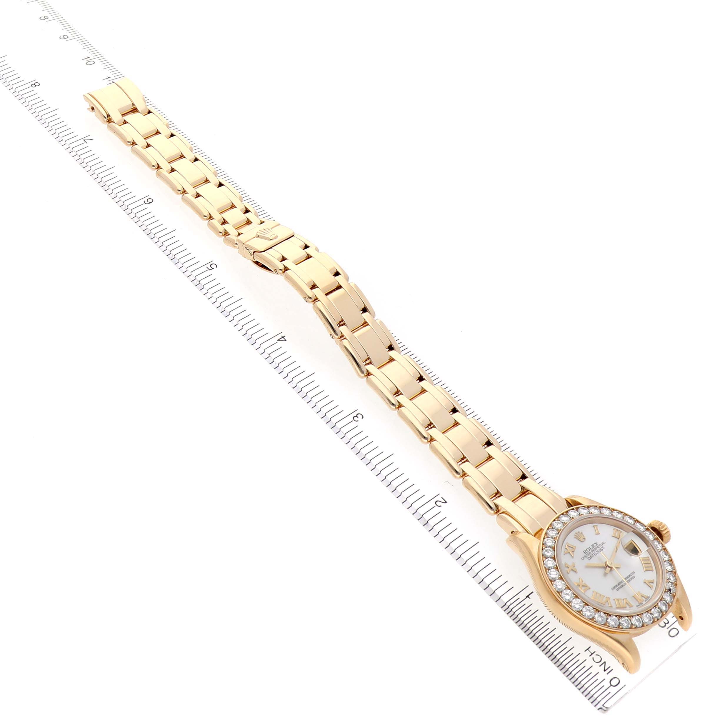 The Rolex Pearlmaster 69298 Women's Yellow Gold Mother of Pearl Dial 69298 Women's Yellow Gold Mother of Pearl Dial watch is shown at a diagonal angle, displaying the face, bezel, and full bracelet alongside a ruler.