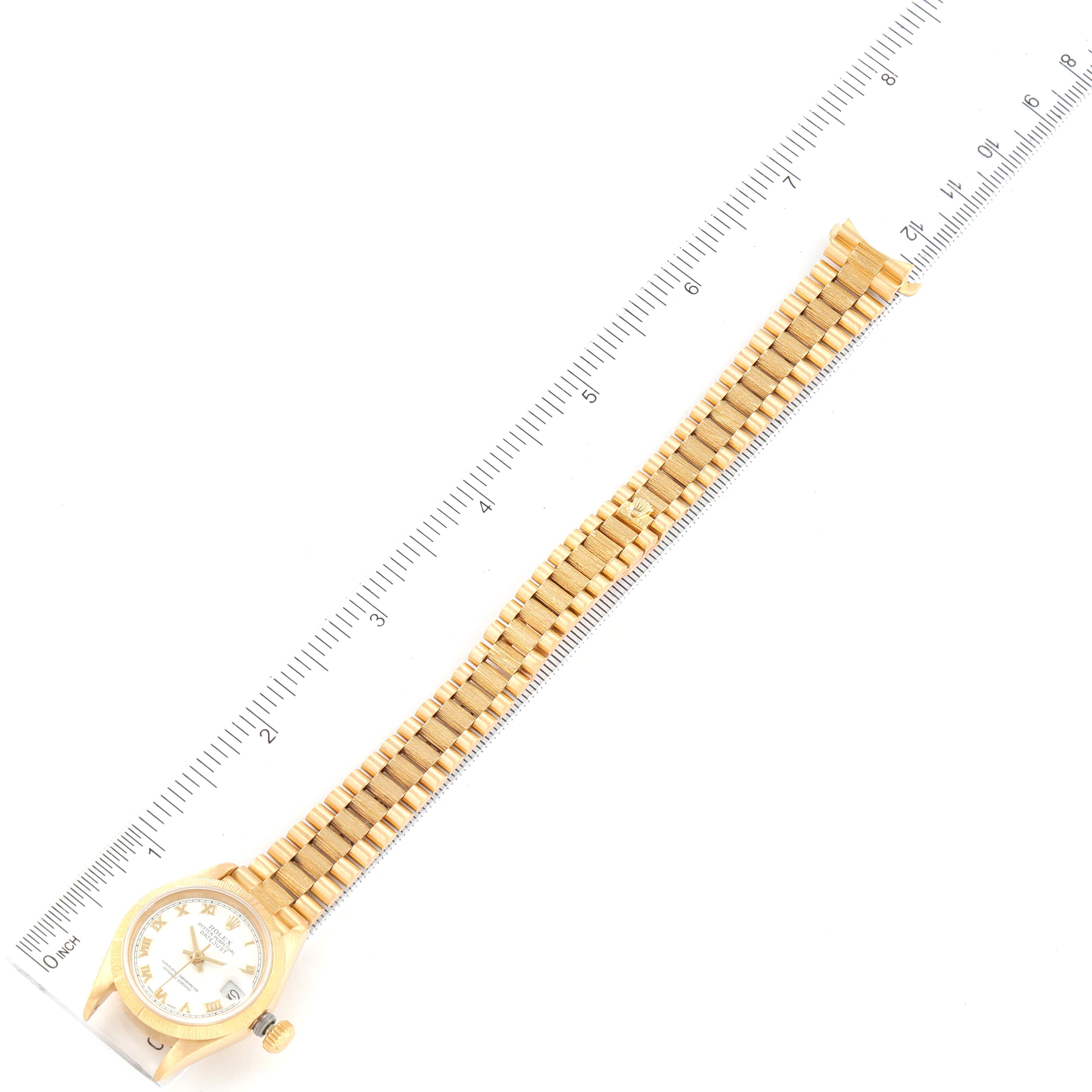 This image shows a Rolex President 69278 Women
s Yellow Gold White Dial 69278 Women
s Yellow Gold White Dial model watch laid flat with a ruler for size reference.