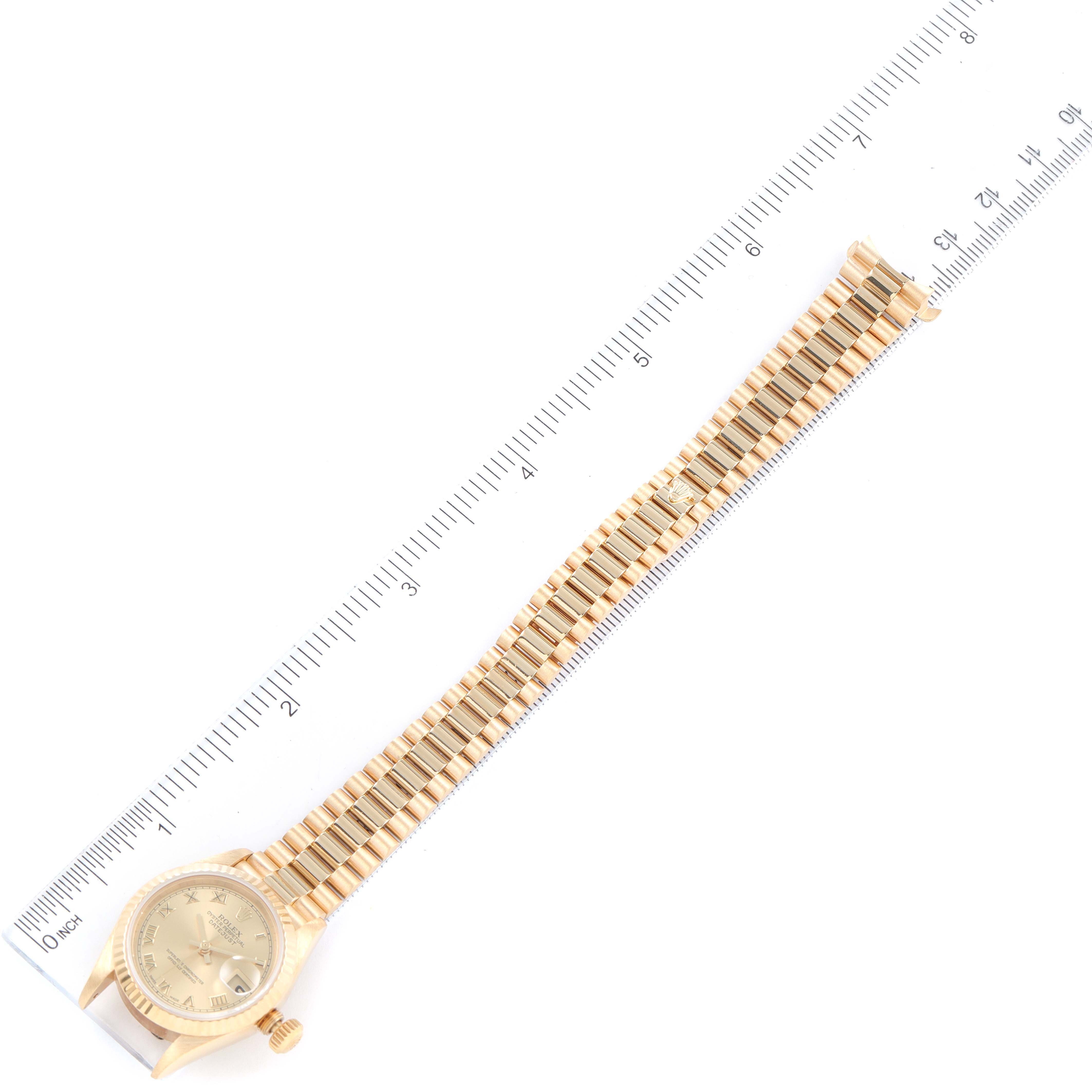 The image shows a top-down view of a Rolex President 79178 Women
s Yellow Gold Champagne Dial 79178 Women
s Yellow Gold Champagne Dial model watch, including its face, bracelet, and a ruler for scale.