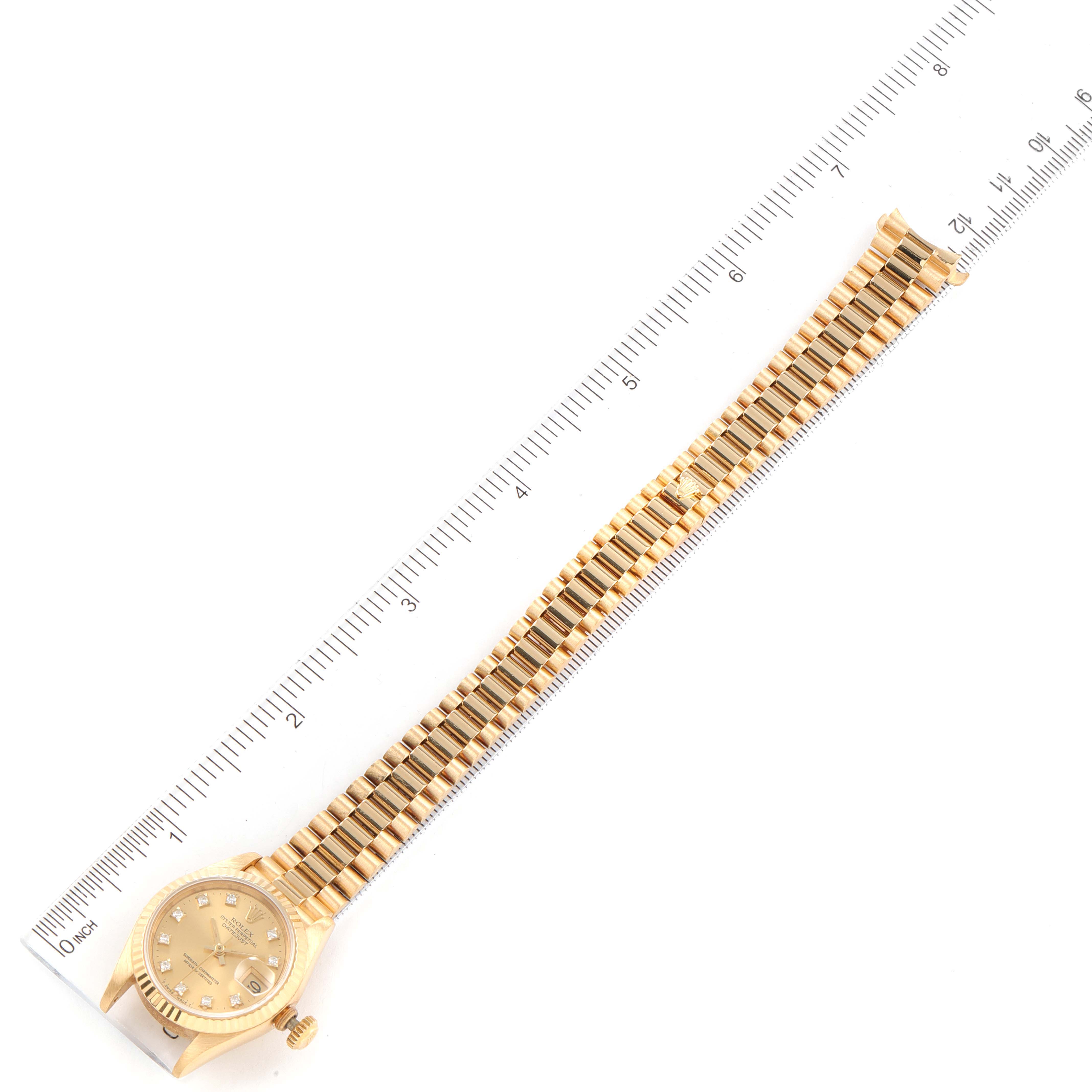 This image shows the face, bezel, and full bracelet of a Rolex President 69178 Women
s Yellow Gold Champagne Dial 69178 Women
s Yellow Gold Champagne Dial model watch laid next to a measuring ruler.