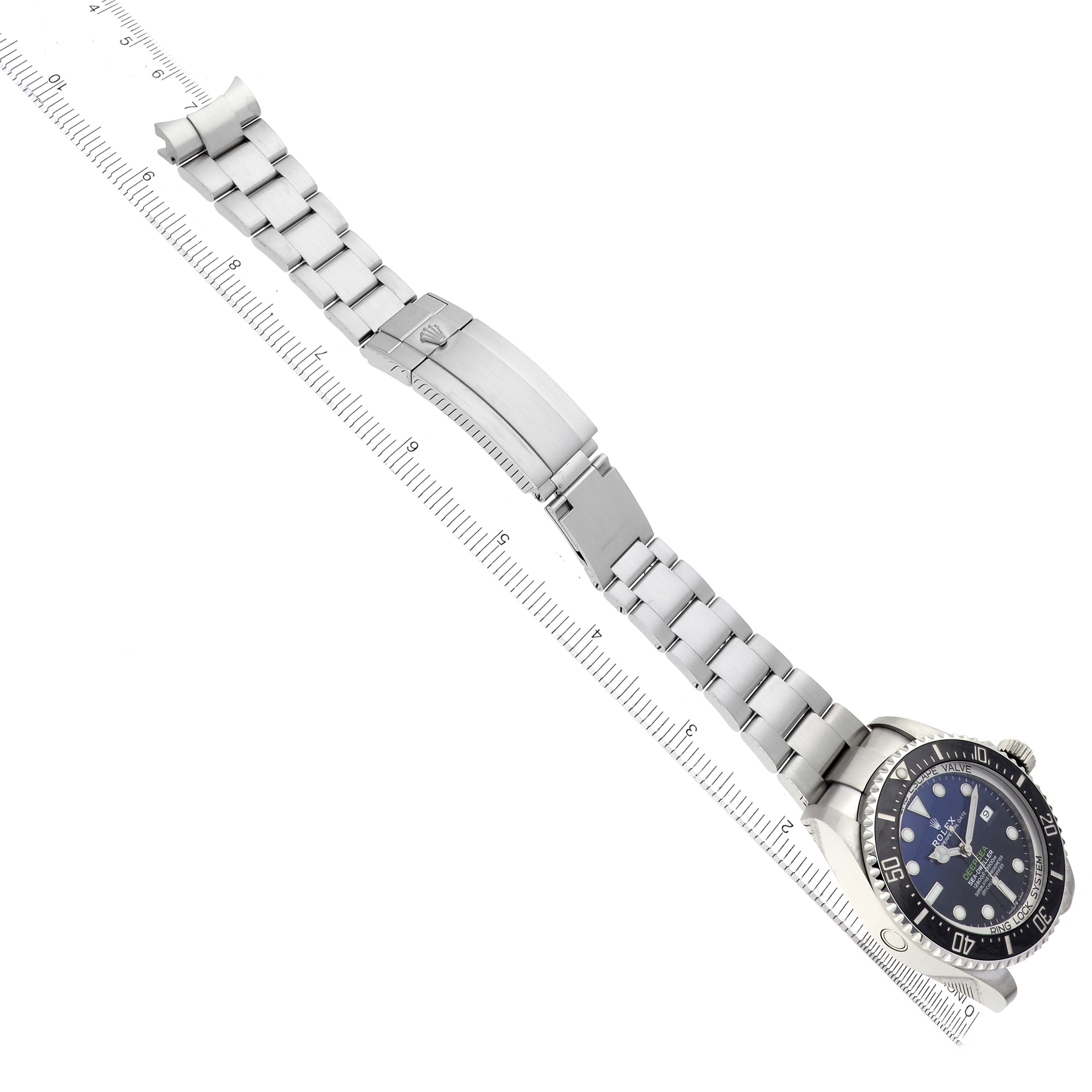 The Rolex Sea-Dweller 126660 Men's Stainless Steel Blue Dial watch is shown at an angled top view, displaying the bracelet and clasp extended alongside a ruler.