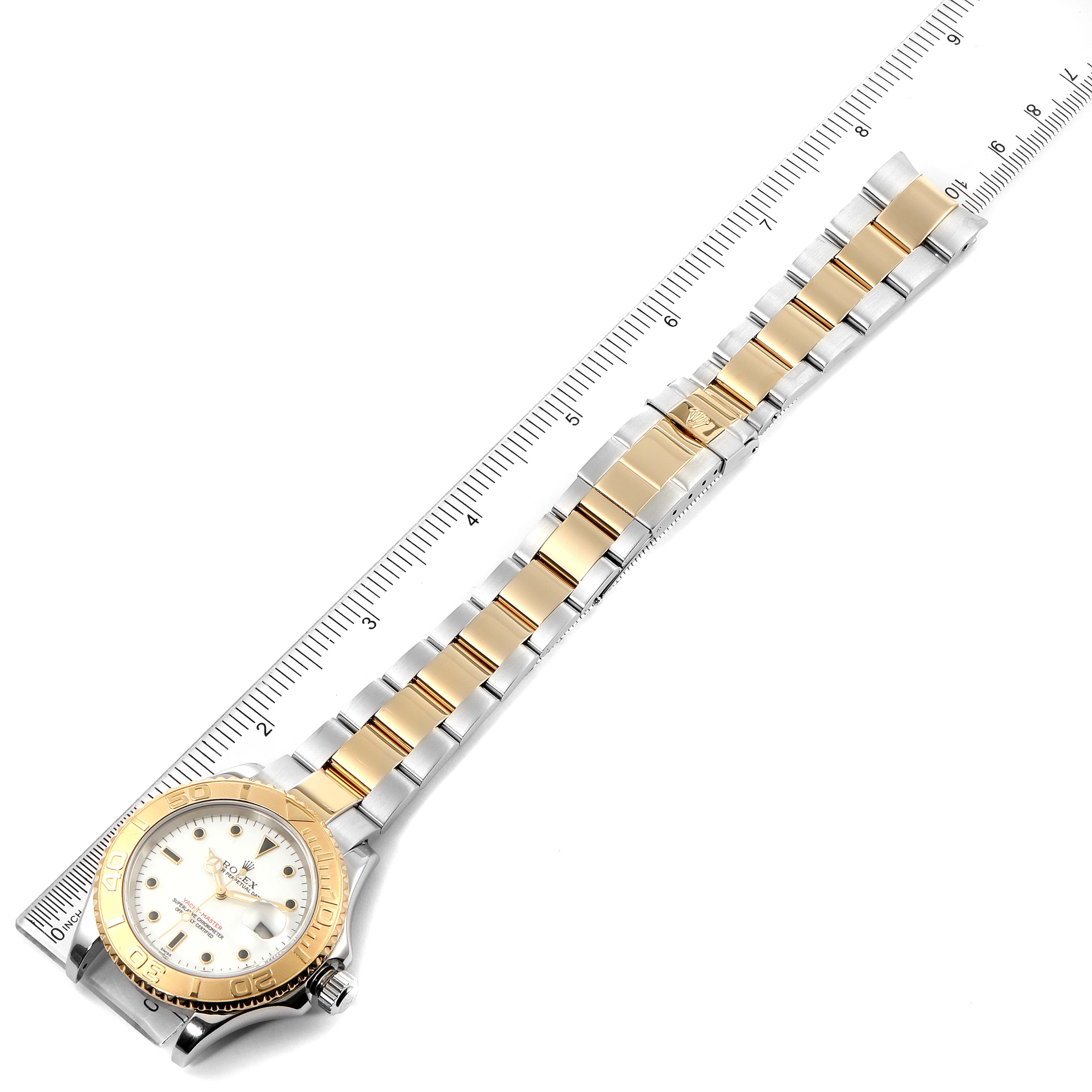 The image shows a Rolex Yacht-Master 16623 Men's Steel and Gold (two tone) White Dial 16623 Men's Steel and Gold (two tone) White Dial watch angled diagonally, displaying the full face, bezel, and bracelet next to a ruler.