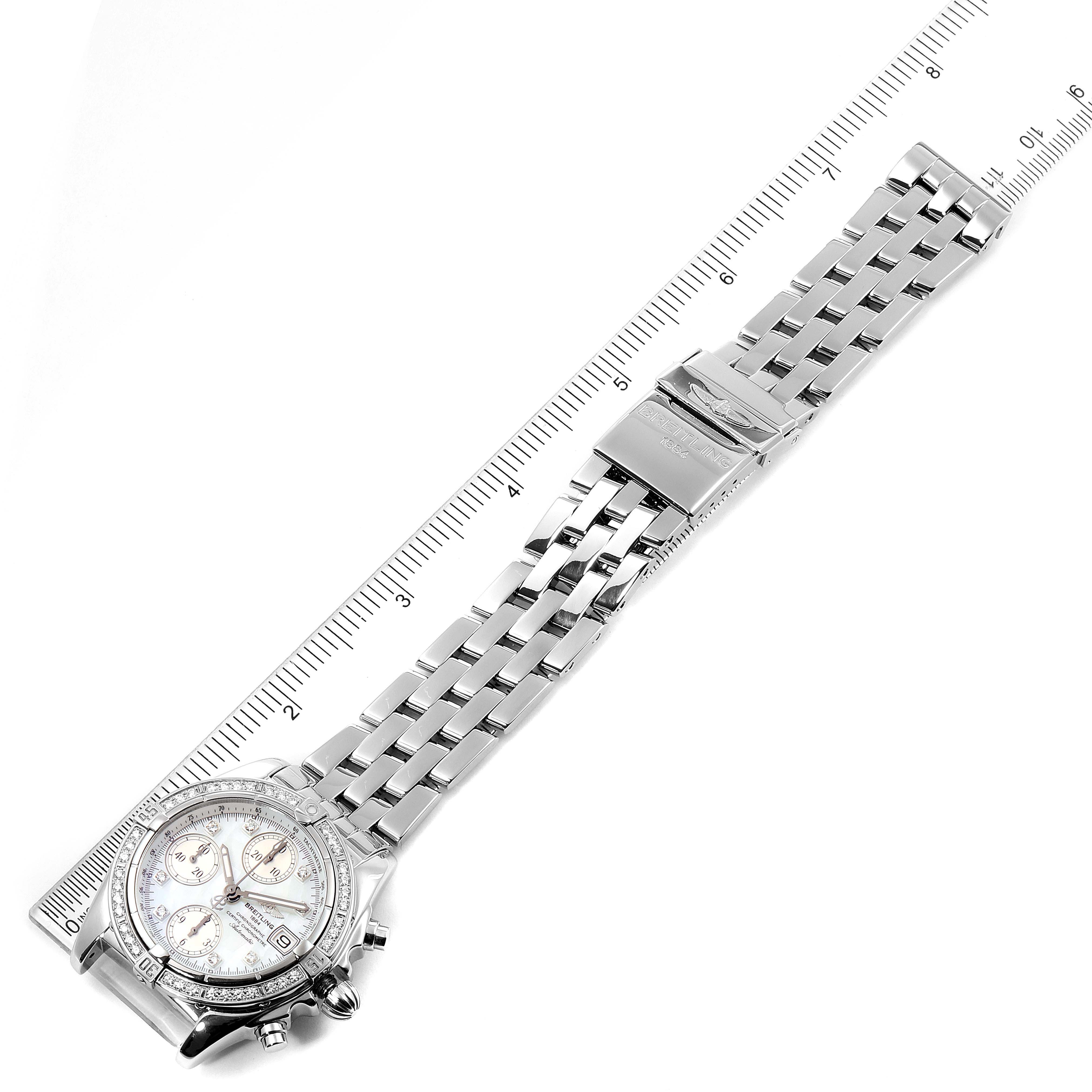 The image shows the Breitling Windrider A13358 Men's Stainless Steel Mother of Pearl Dial A13358 Men's Stainless Steel Mother of Pearl Dial watch laid flat, displaying the face, bracelet, and clasp, with a ruler for scale.