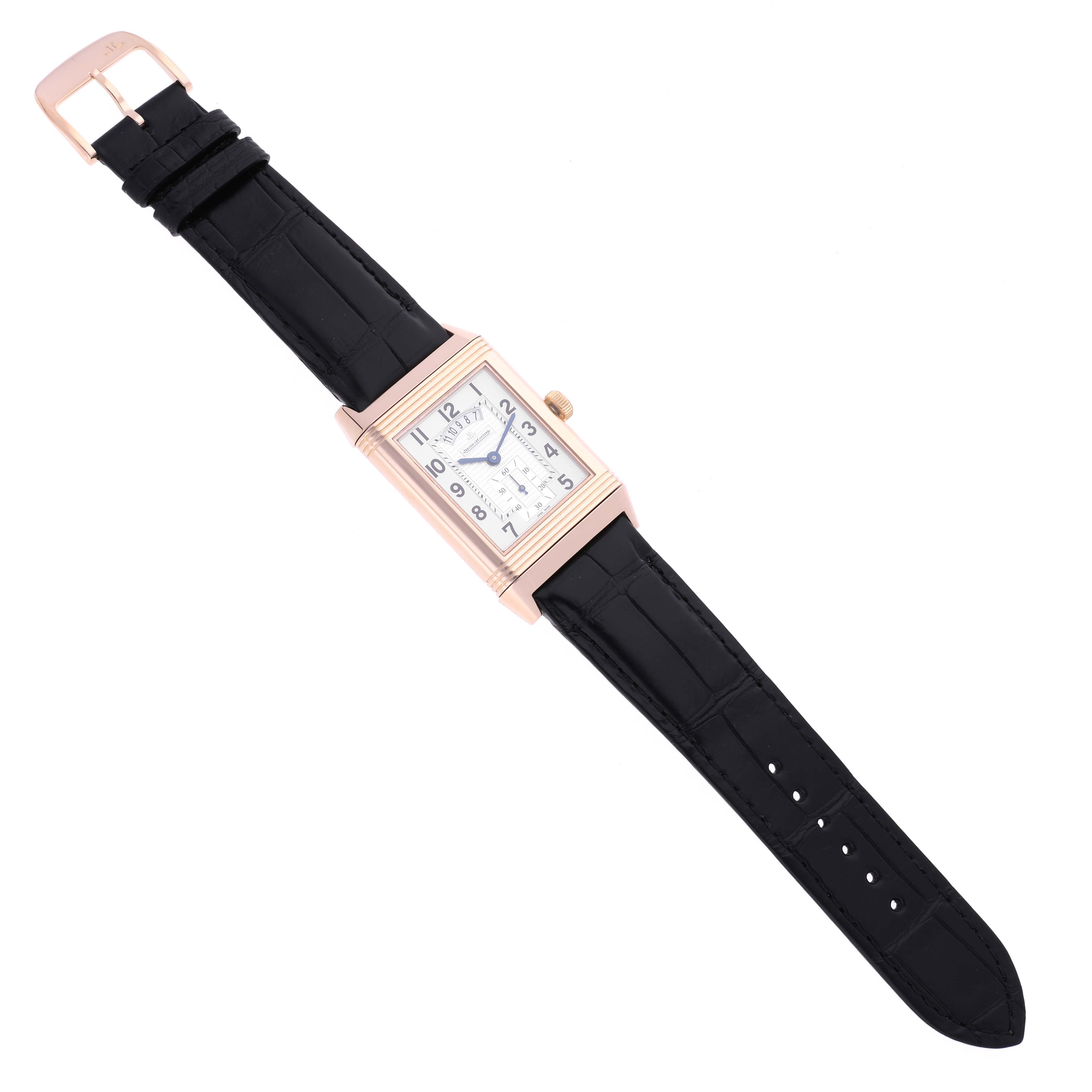 The Jaeger-LeCoultre Reverso watch is shown at an angled top view, displaying the case, face, crown, and black strap.
