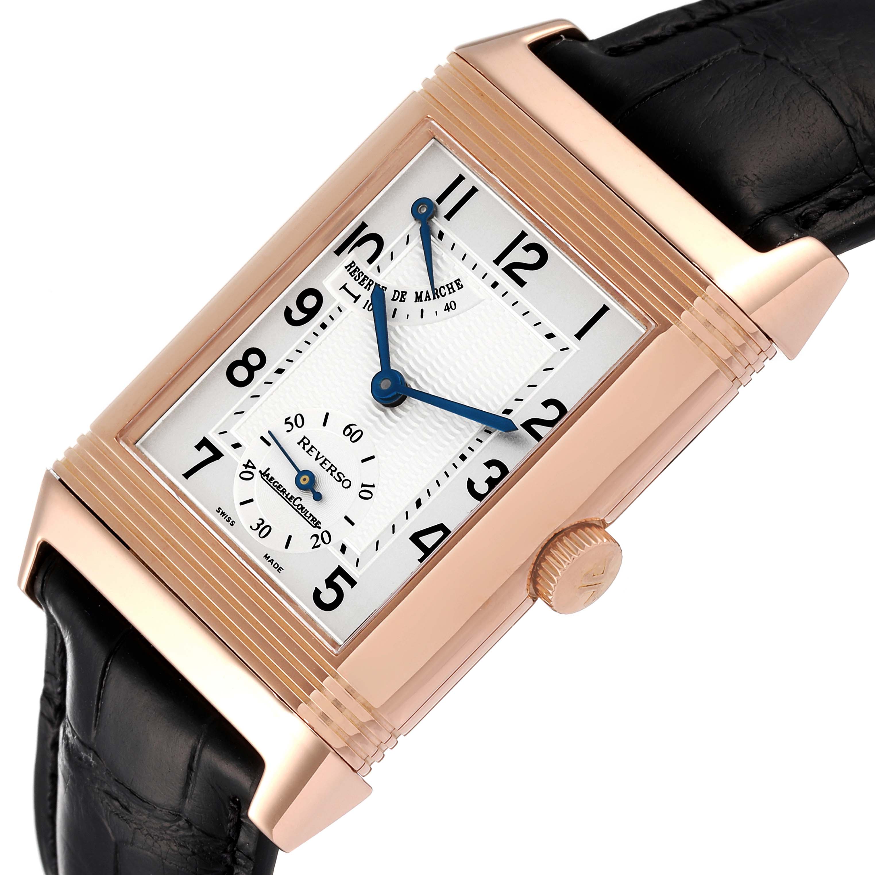 The image shows a close-up view of the face and crown of a Jaeger-LeCoultre Reverso watch, highlighting its rectangular case and leather strap.