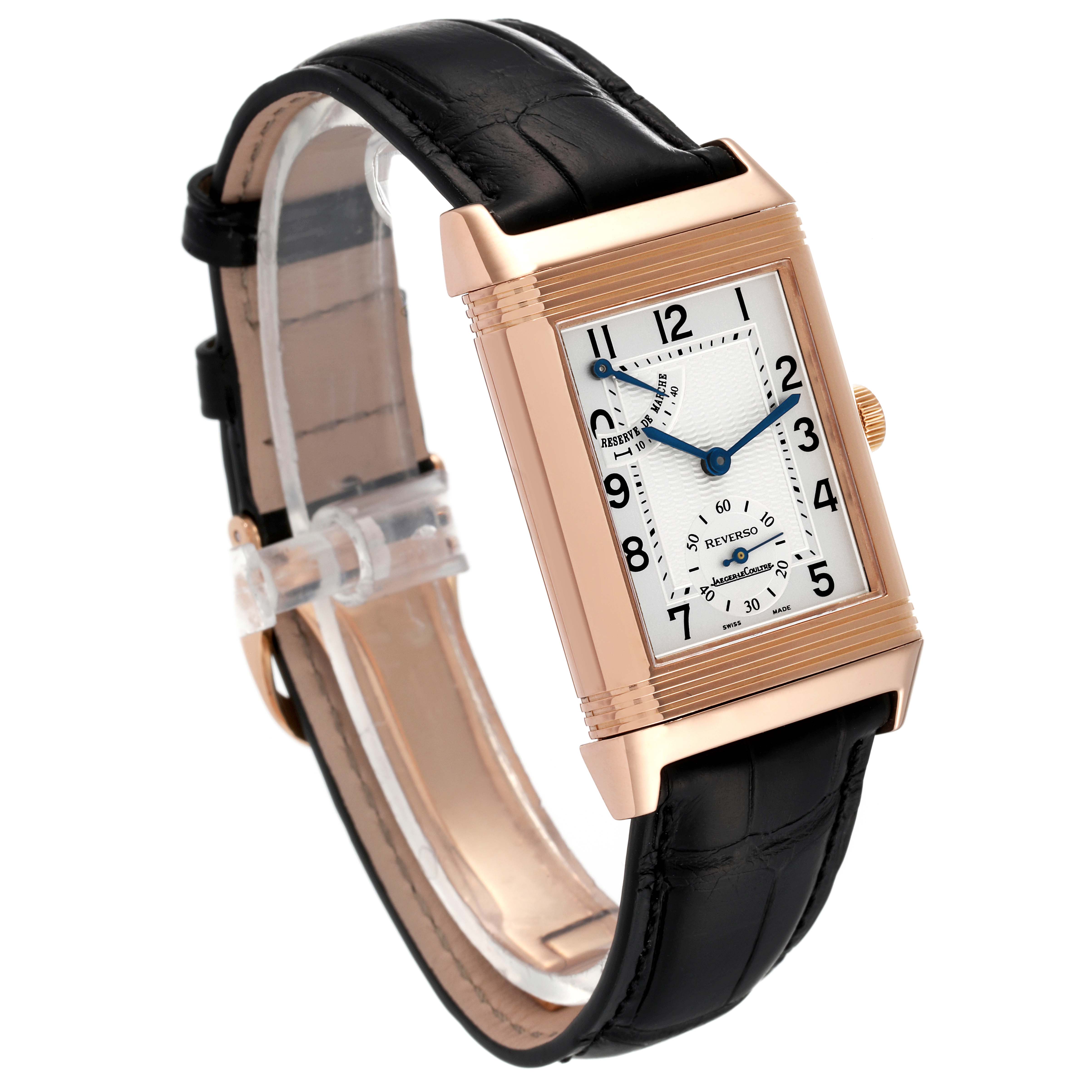 The image shows a Jaeger LeCoultre Reverso Q2702420 Men
s Rose Gold Silver Dial Q2702420 Men
s Rose Gold Silver Dial watch at an angle, displaying its face, rectangular case, crown, and black leather strap.