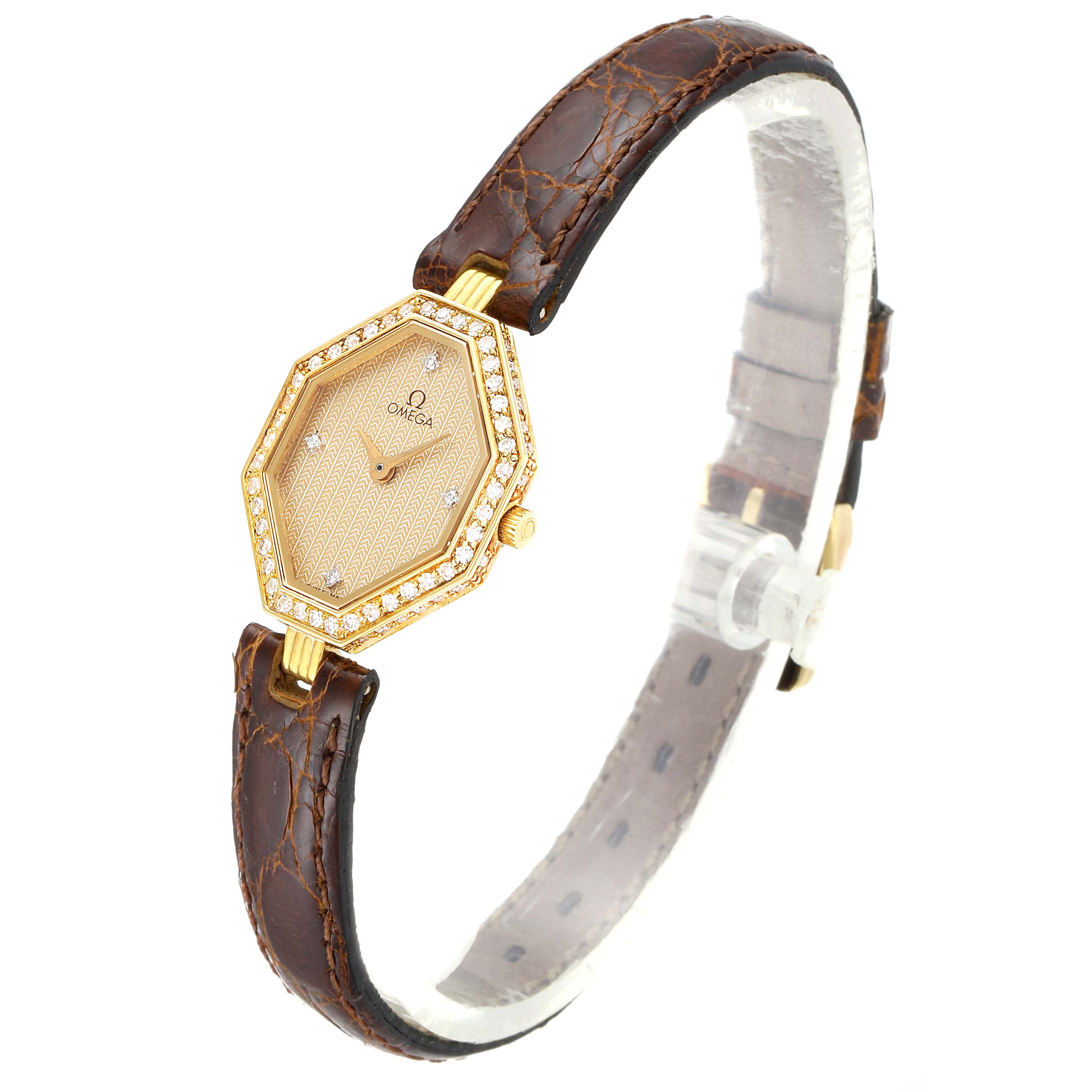 The Omega 1450 Women's Yellow Gold Champagne Dial 1450 Women's Yellow Gold Champagne Dial DeVille Mini Yellow Gold Diamond Cocktail Ladies Watch 1450 is shown at a side angle, displaying the hexagonal face and brown leather strap.