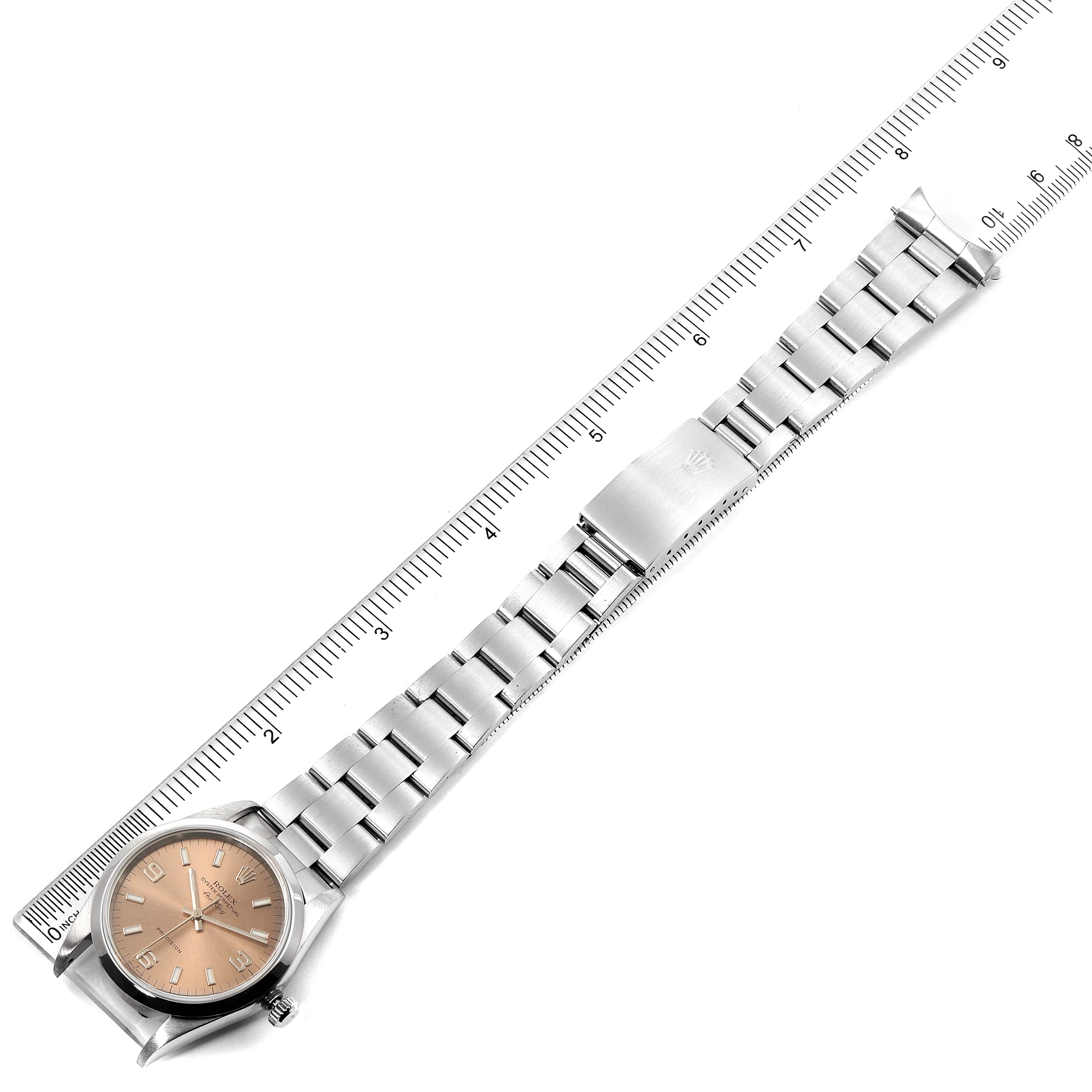 The image shows a top-down view of a Rolex Air-King 14000 Men's Stainless Steel Pink Dial 14000 Men's Stainless Steel Pink Dial watch and its metal bracelet aligned along a ruler.