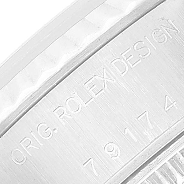 This close-up image shows the engraved side of a Rolex Datejust 79174 Women's Stainless Steel Mother of Pearl Dial 79174 Women's Stainless Steel Mother of Pearl Dial watch, displaying the text "ORIG. ROLEX DESIGN" and serial numbers.