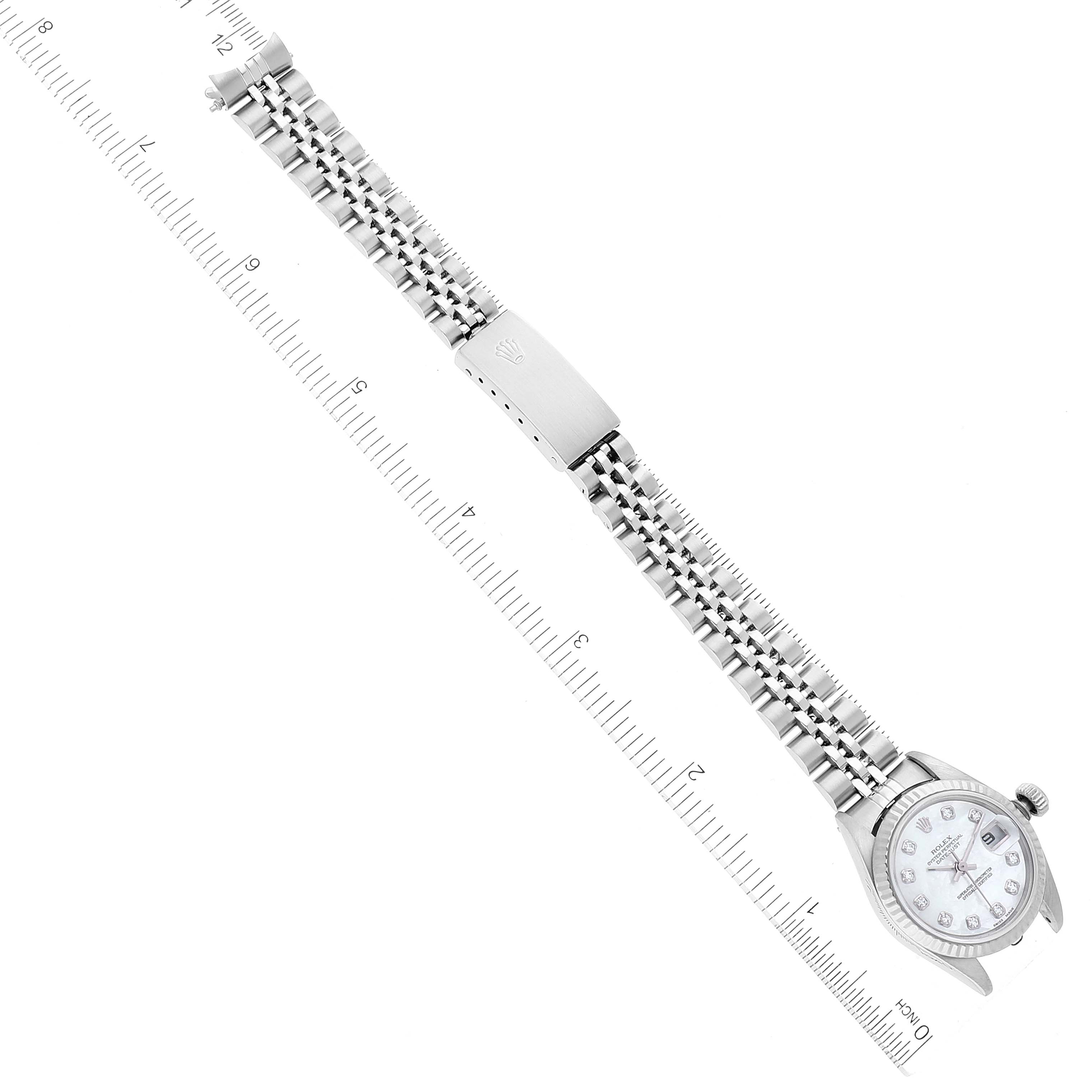 The image shows a Rolex Datejust 79174 Women's Stainless Steel Mother of Pearl Dial 79174 Women's Stainless Steel Mother of Pearl Dial watch laid flat beside a ruler, highlighting its bracelet and face from a top-down angle.