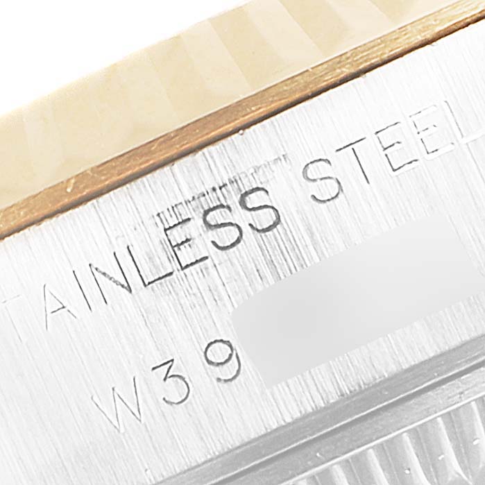 This close-up image of the Rolex Datejust 69173 Women
s Steel and Gold (two tone) Champagne Dial 69173 Women
s Steel and Gold (two tone) Champagne Dial model shows the stainless steel casing with partial serial number and some wooden surfaces.