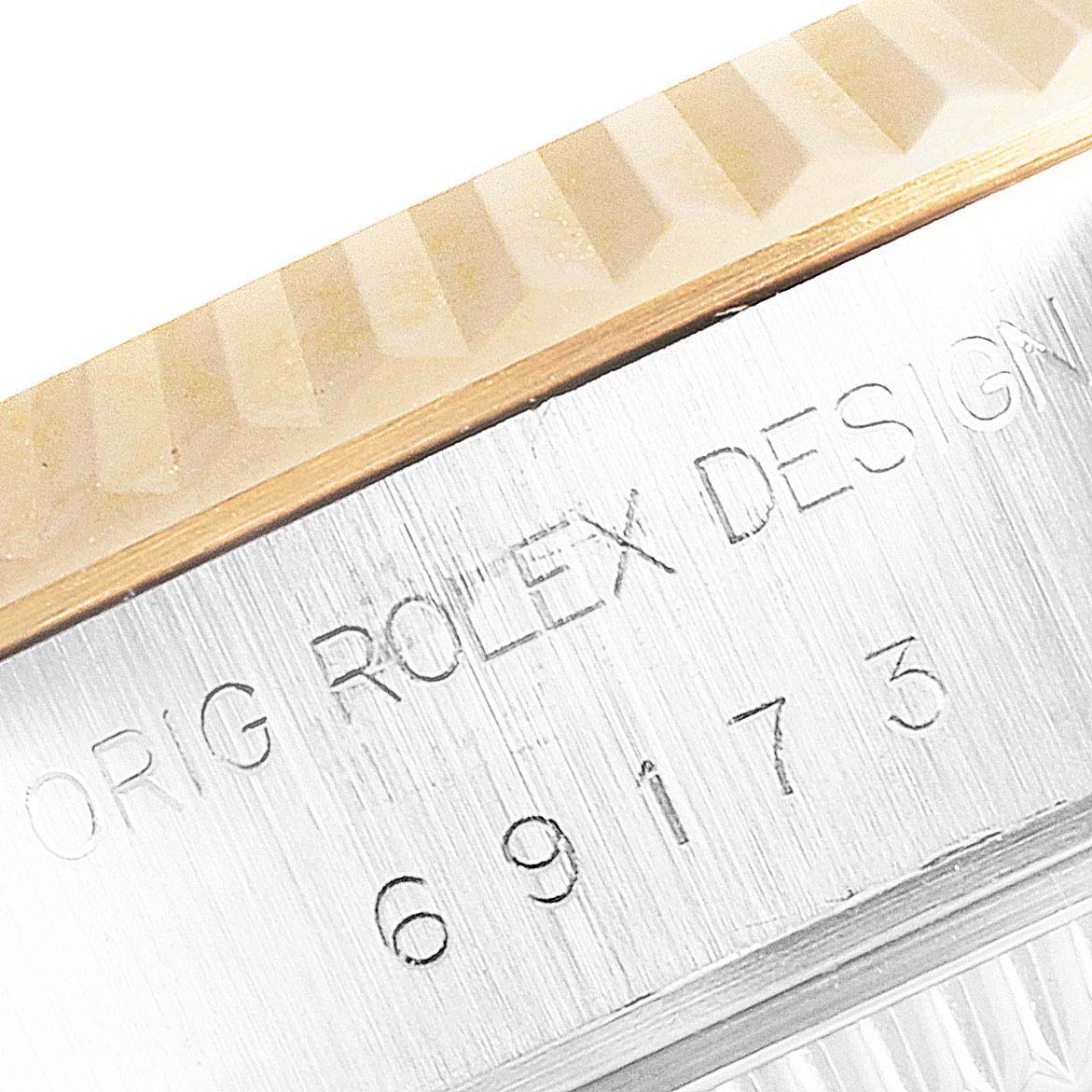 This image shows a close-up of the case side of a Rolex Datejust 69173 Women's Steel and Gold (two tone) Champagne Dial 69173 Women's Steel and Gold (two tone) Champagne Dial, featuring the serial and model numbers along with the fluted bezel.