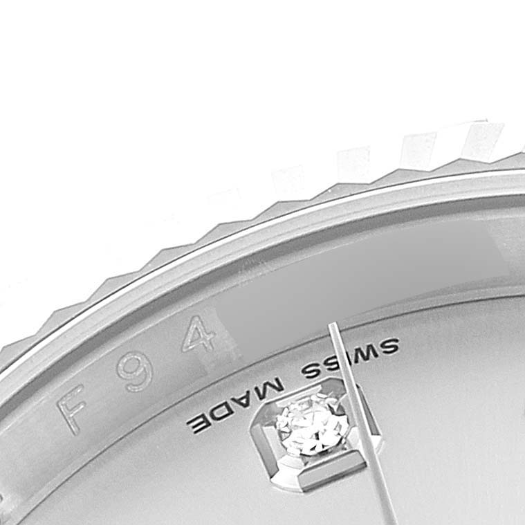 This close-up image of a Rolex Datejust 116139 Men
s White Gold Silver Dial 116139 Men
s White Gold Silver Dial watch shows part of the dial, a diamond marker, and a section of the fluted bezel.