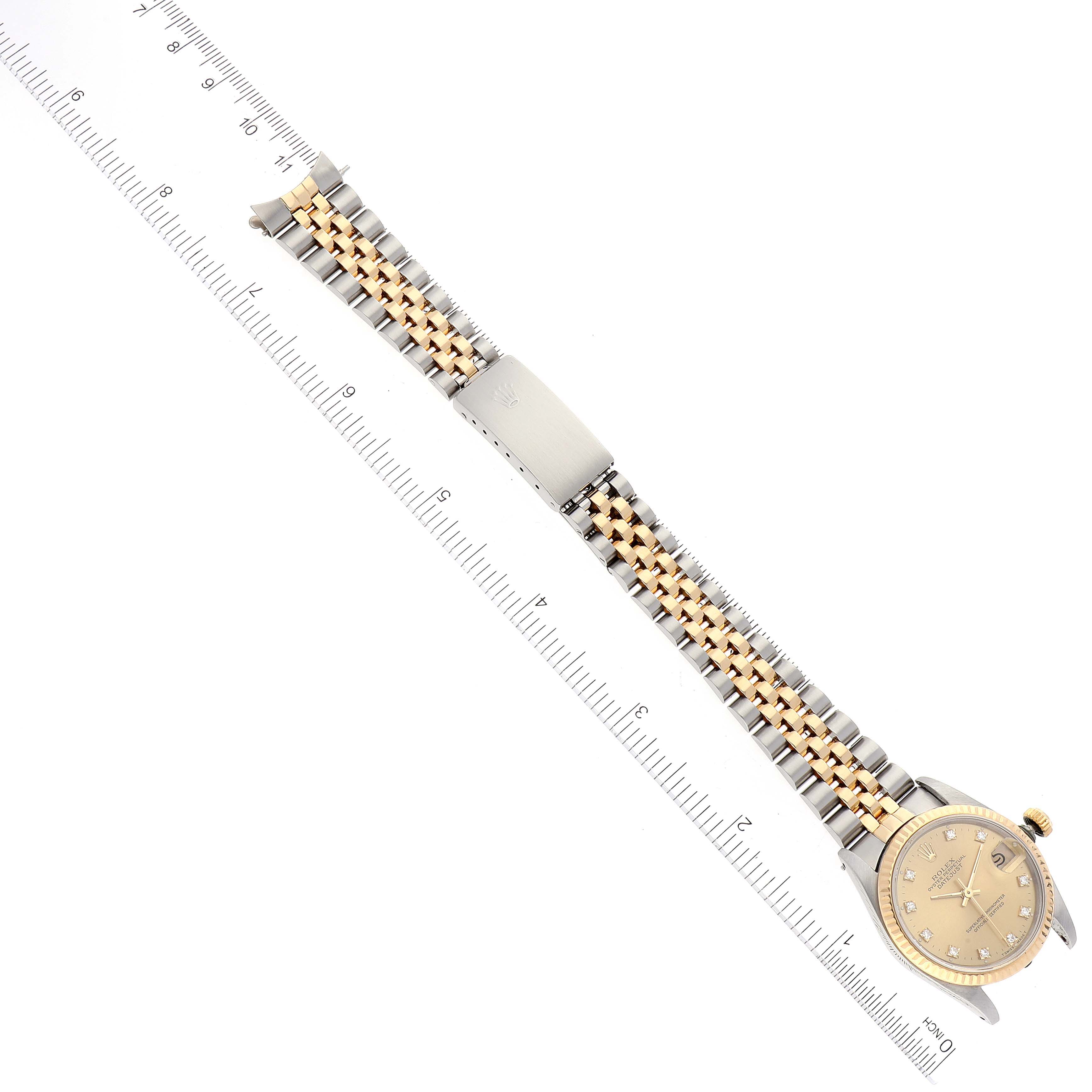 The image shows a Rolex Mid-Size 68273 Women
s Steel and Gold (two tone) Champagne Dial 68273 Women
s Steel and Gold (two tone) Champagne Dial watch placed alongside a ruler, viewed from above.