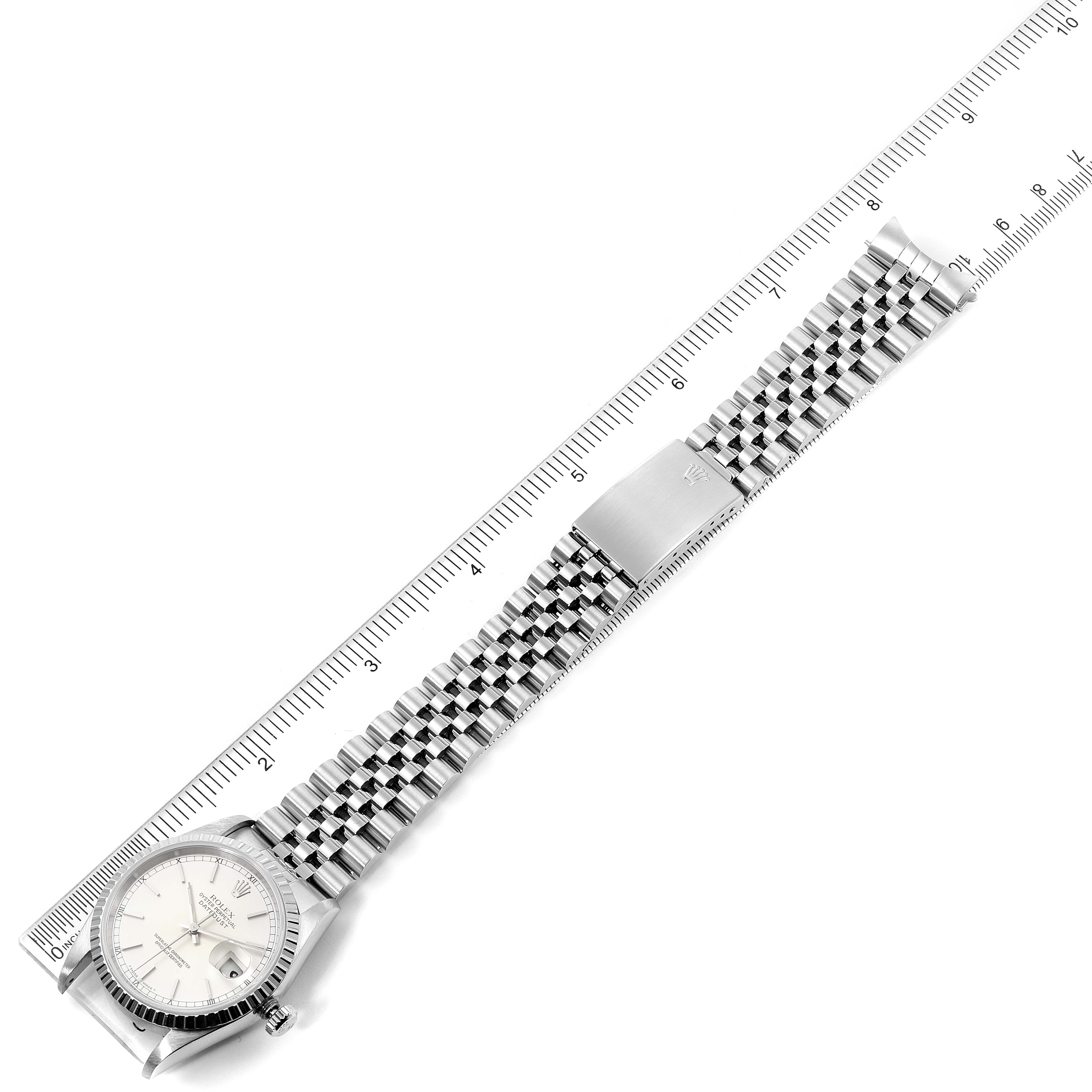 The Rolex Datejust 16220 Men's Stainless Steel Silver Dial 16220 Men's Stainless Steel Silver Dial watch is shown from above, displaying its face, bracelet, and clasp alongside a ruler for scale.