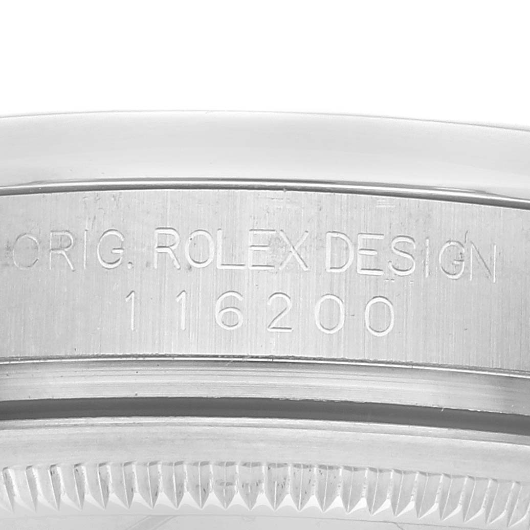 The image shows a close-up side view of the Rolex Datejust 116200 Men's Stainless Steel Black Dial watch case, displaying the engraved design and model number.