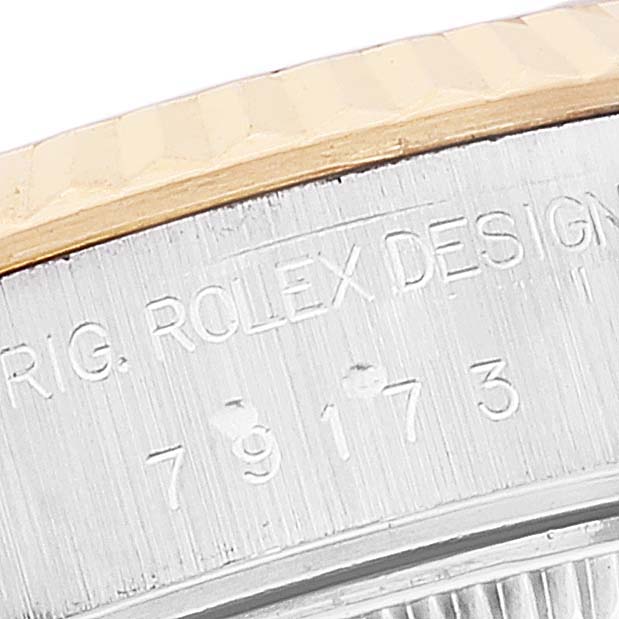 This close-up image shows the side engraving and part of the fluted bezel of a Rolex Datejust 79173 Women's Steel and Gold (two tone) Champagne Dial 79173 Women's Steel and Gold (two tone) Champagne Dial watch.