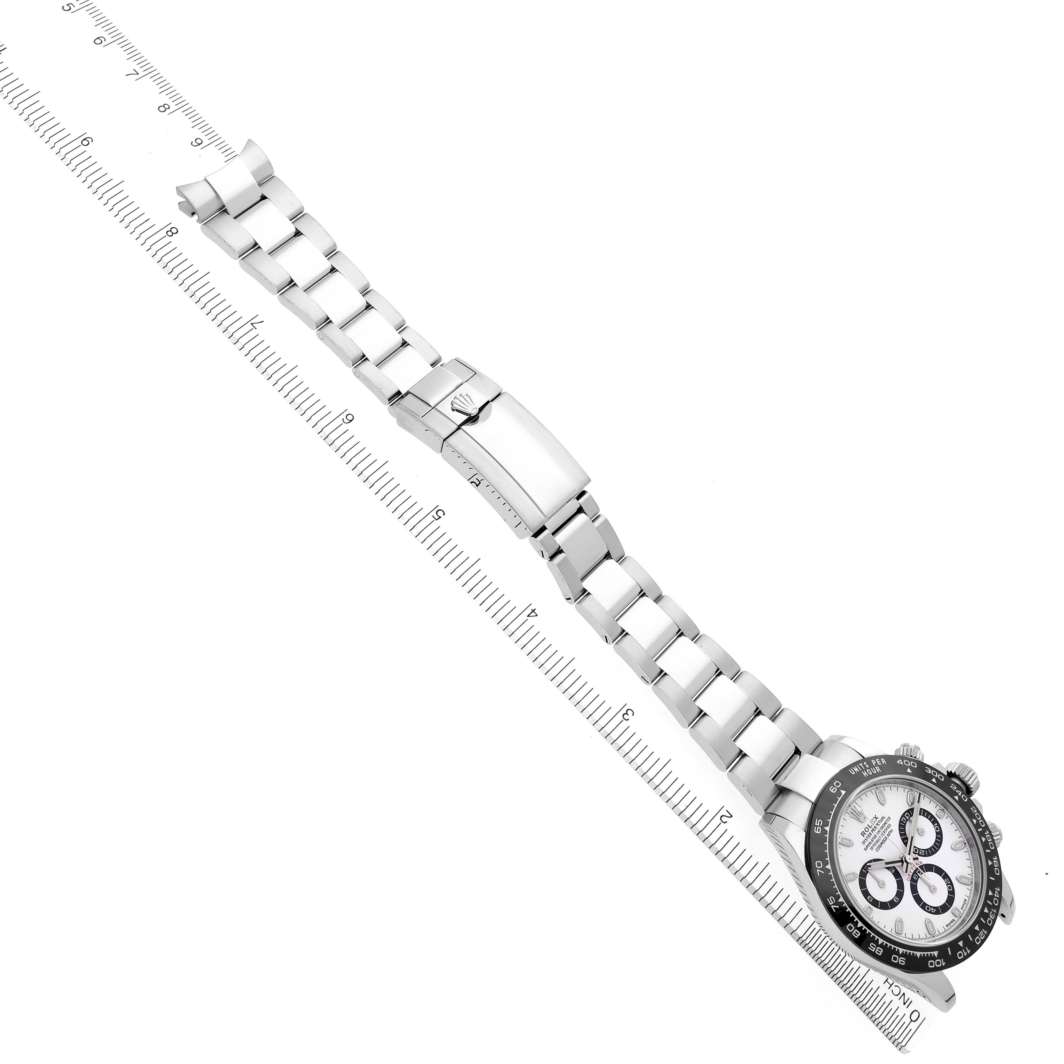 The image shows a Rolex Daytona 116500LN Men's Stainless Steel White Dial 116500LN Men's Stainless Steel White Dial watch laid flat at a diagonal angle, highlighting the bracelet and clasp alongside a measuring scale.