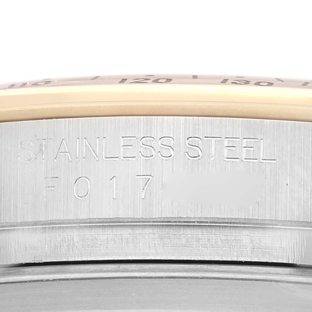 The image shows a close-up of the side of a Rolex Daytona 116523 Men's Steel and Gold (two tone) Champagne Dial 116523 Men's Steel and Gold (two tone) Champagne Dial watch made of stainless steel, displaying its engraved text.