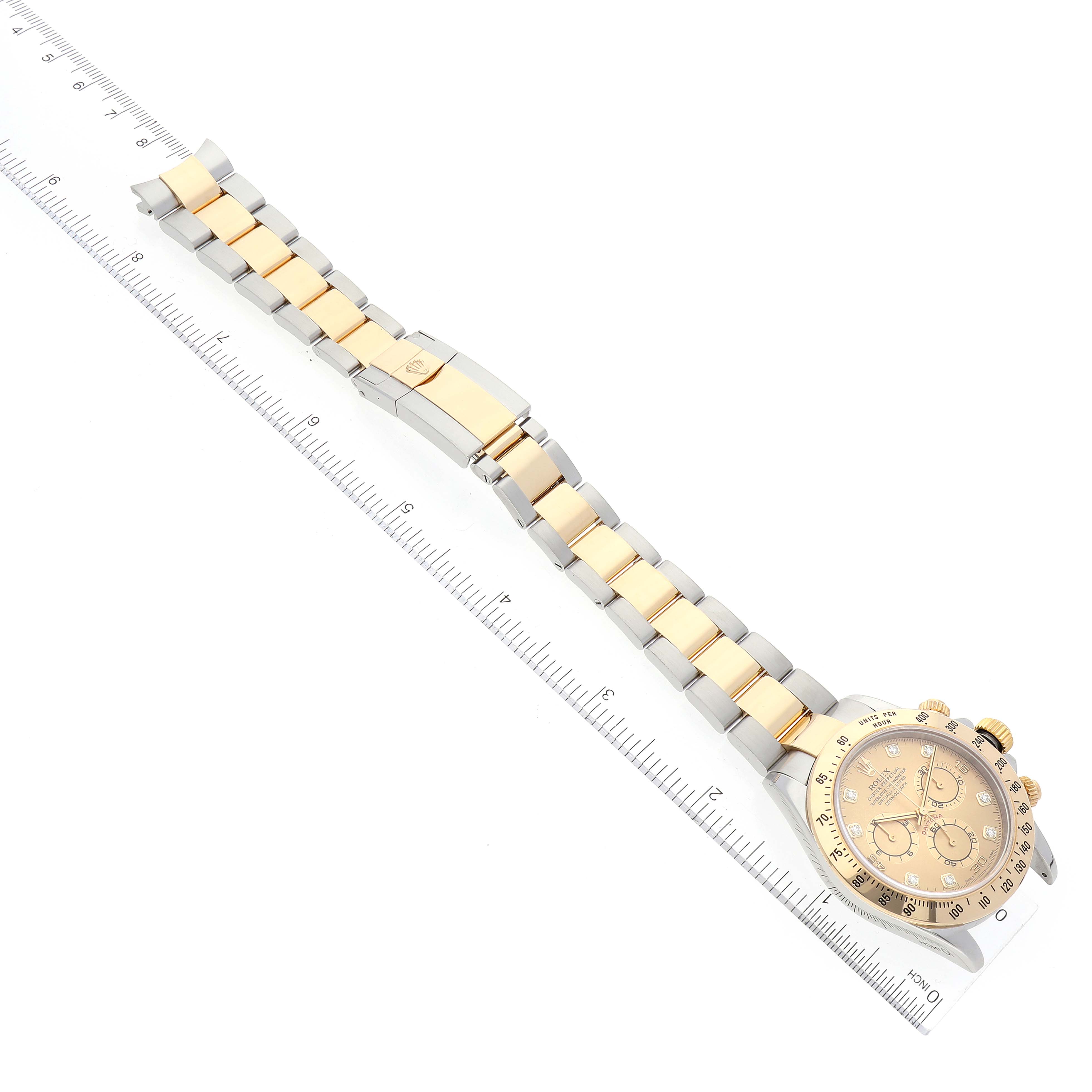 The image shows a Rolex Daytona 116523 Men's Steel and Gold (two tone) Champagne Dial 116523 Men's Steel and Gold (two tone) Champagne Dial watch laid flat with its full bracelet and clasp visible, alongside a measuring ruler.