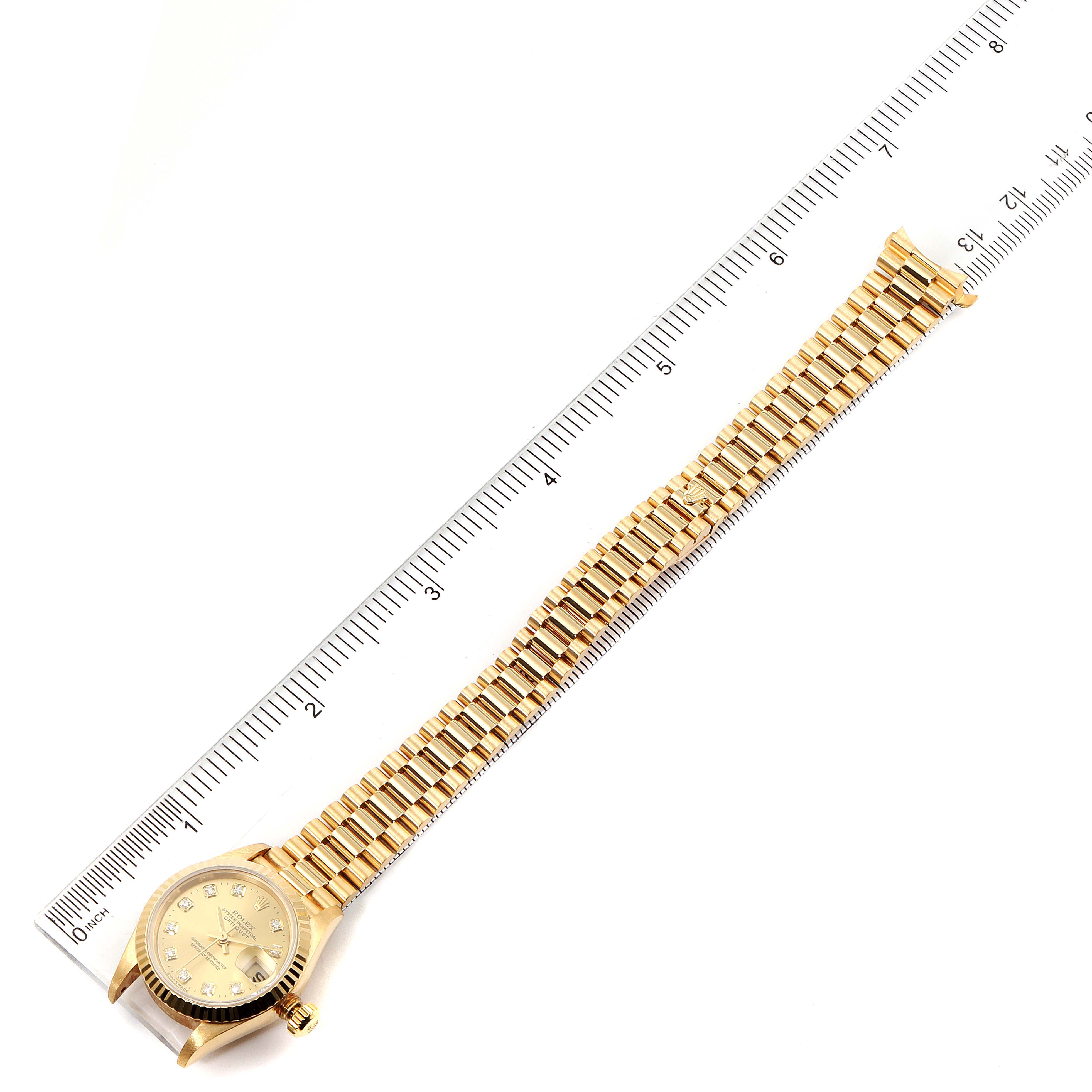 The image shows a Rolex President 79178 Women
s Yellow Gold Champagne Dial 79178 Women
s Yellow Gold Champagne Dial model watch lying flat, with its dial and bracelet extended alongside a ruler.
