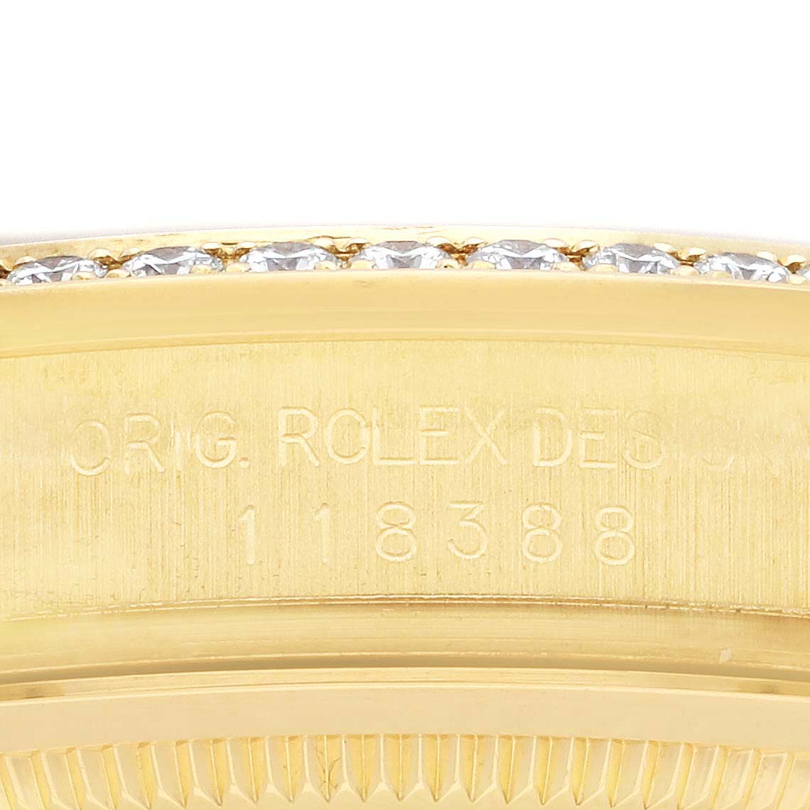 The image shows a close-up of the Rolex President 118388 Men's Yellow Gold Champagne Dial 118388 Men's Yellow Gold Champagne Dial model's engraved case, focusing on the serial number and bezel edge.