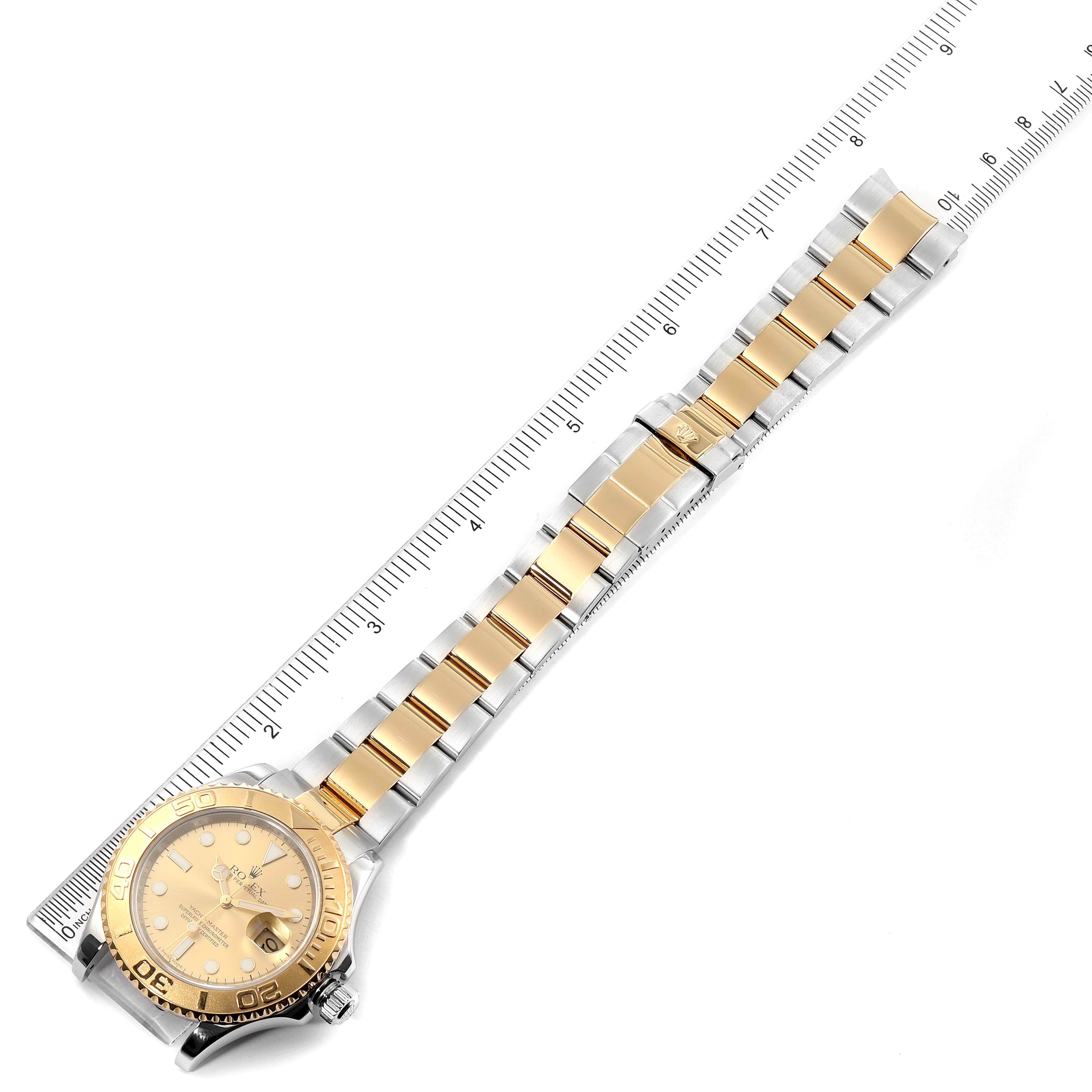 The Rolex Yacht-Master 16623 Men
s Steel and Gold (two tone) Champagne Dial 16623 Men
s Steel and Gold (two tone) Champagne Dial watch is shown from a top-down angle, displaying its face, bezel, and metal strap alongside a measuring ruler.