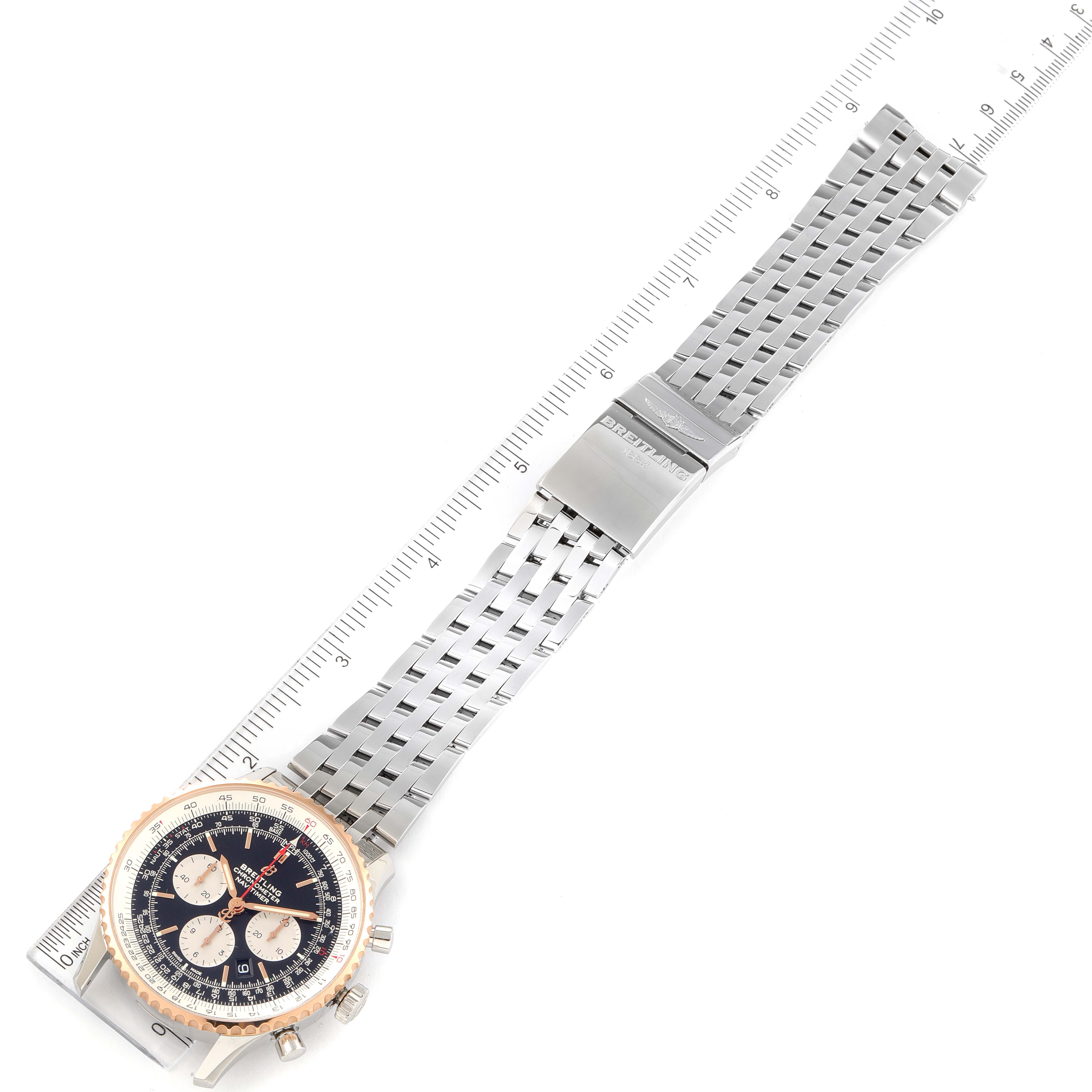 The image shows the full view of a Breitling Navitimer UB0127 Men's Steel and Gold (two tone) Black Dial UB0127 Men's Steel and Gold (two tone) Black Dial watch, including its face, bezel, and metal strap, laid flat with a ruler for scale.