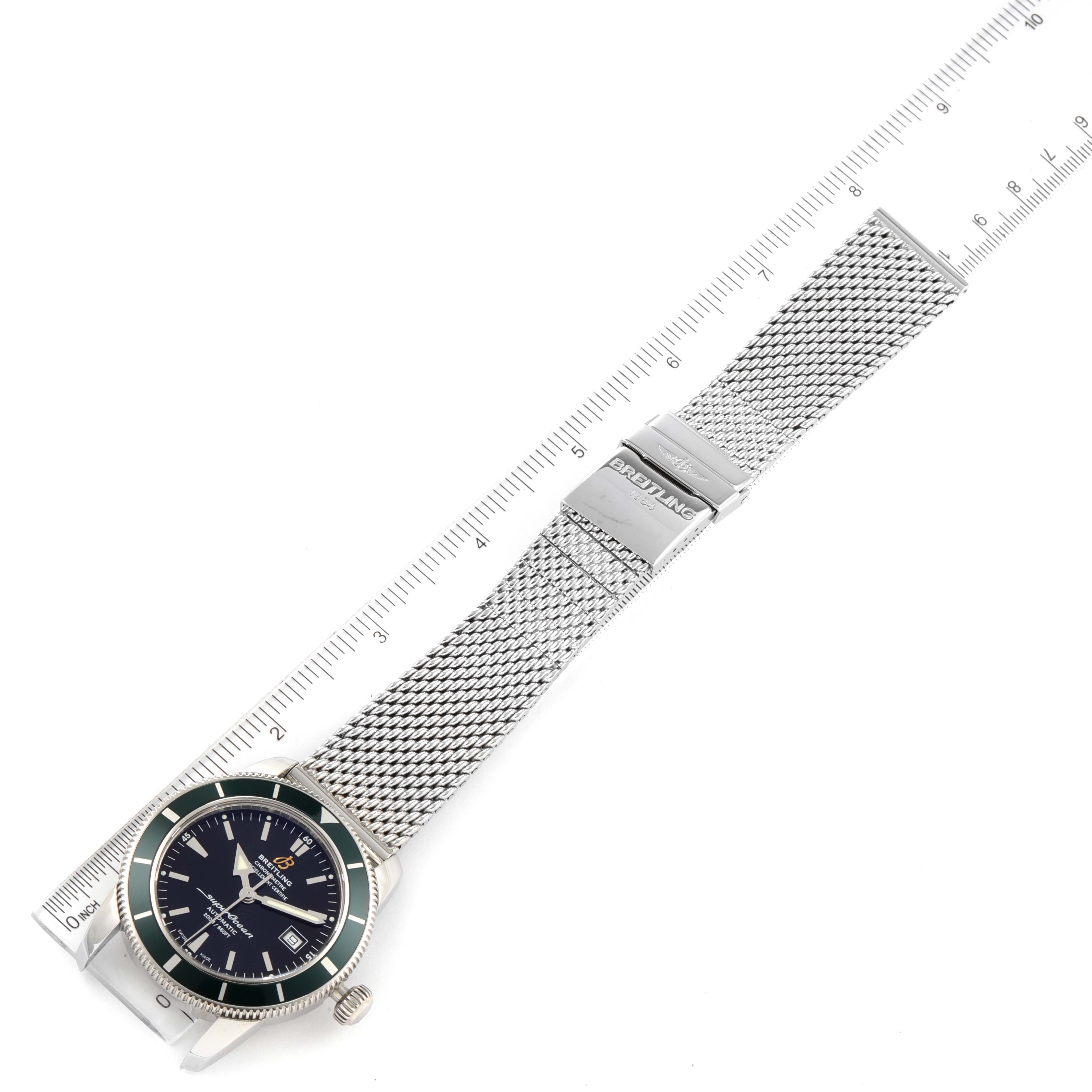 The image shows the Superocean model by Breitling with a metal mesh strap and clasp, positioned alongside a ruler for scale.