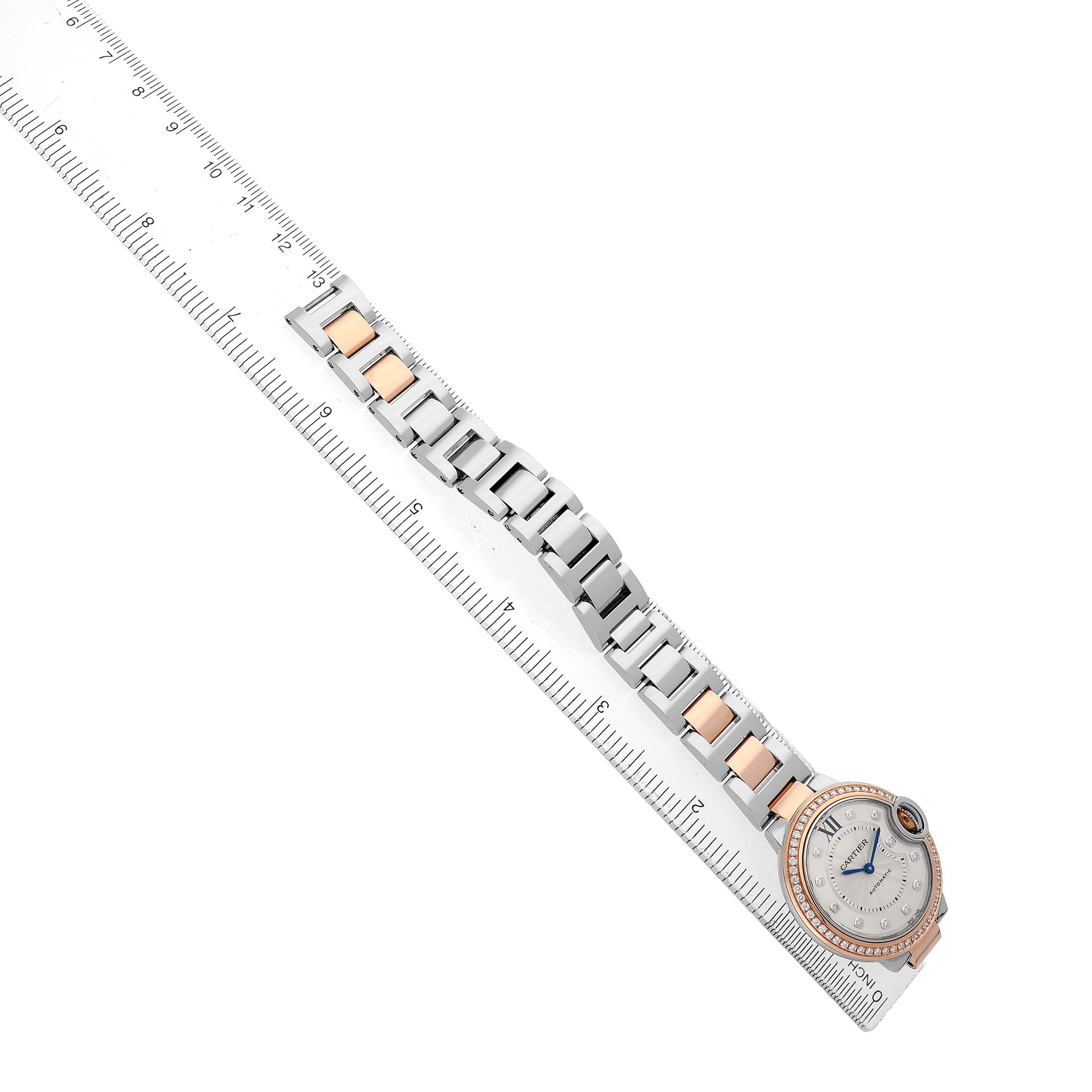 The Cartier Ballon Bleu WE902077 Women's Steel and Gold (two tone) Silver Dial watch is shown from an overhead angle, displaying its full bracelet and dial against a ruler for scale.