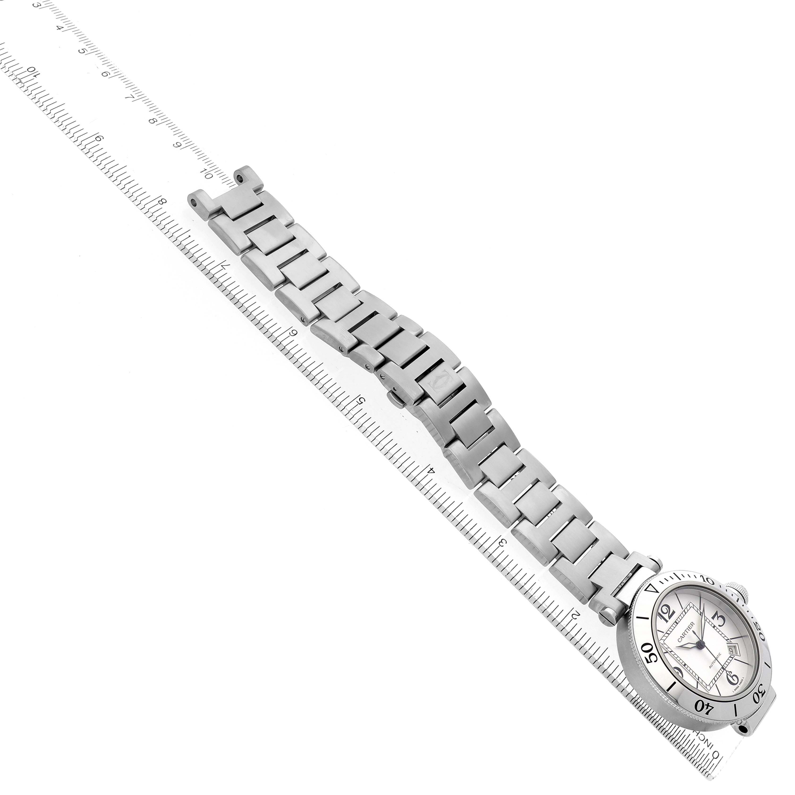 The image shows the Calibre de Cartier watch from a top angle, displaying its face and metal bracelet along a ruler.