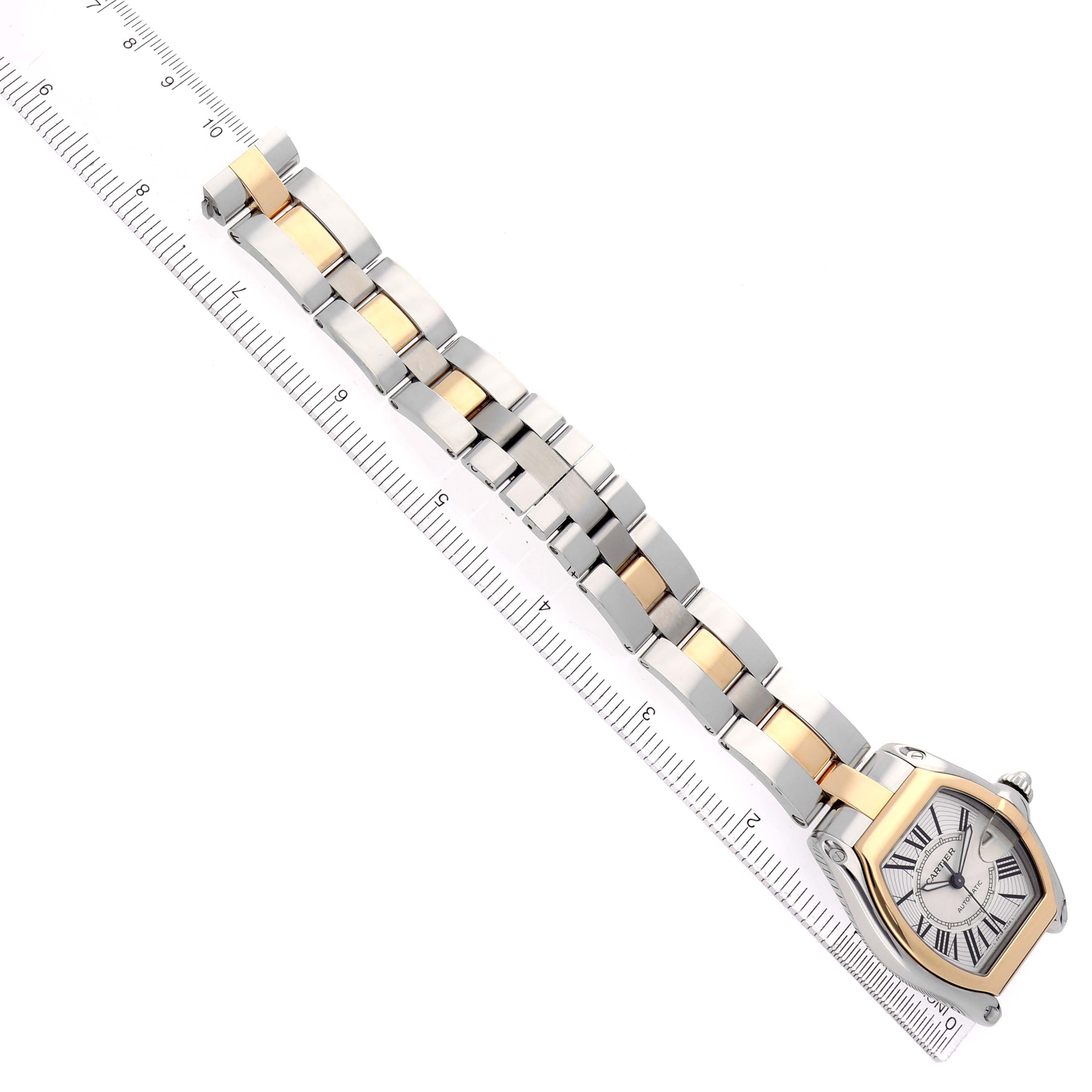 The Cartier Roadster W62031Y4 Men's Steel and Gold (two tone) Silver Dial watch is angled diagonally, showing the face and full metal bracelet alongside a ruler for scale.