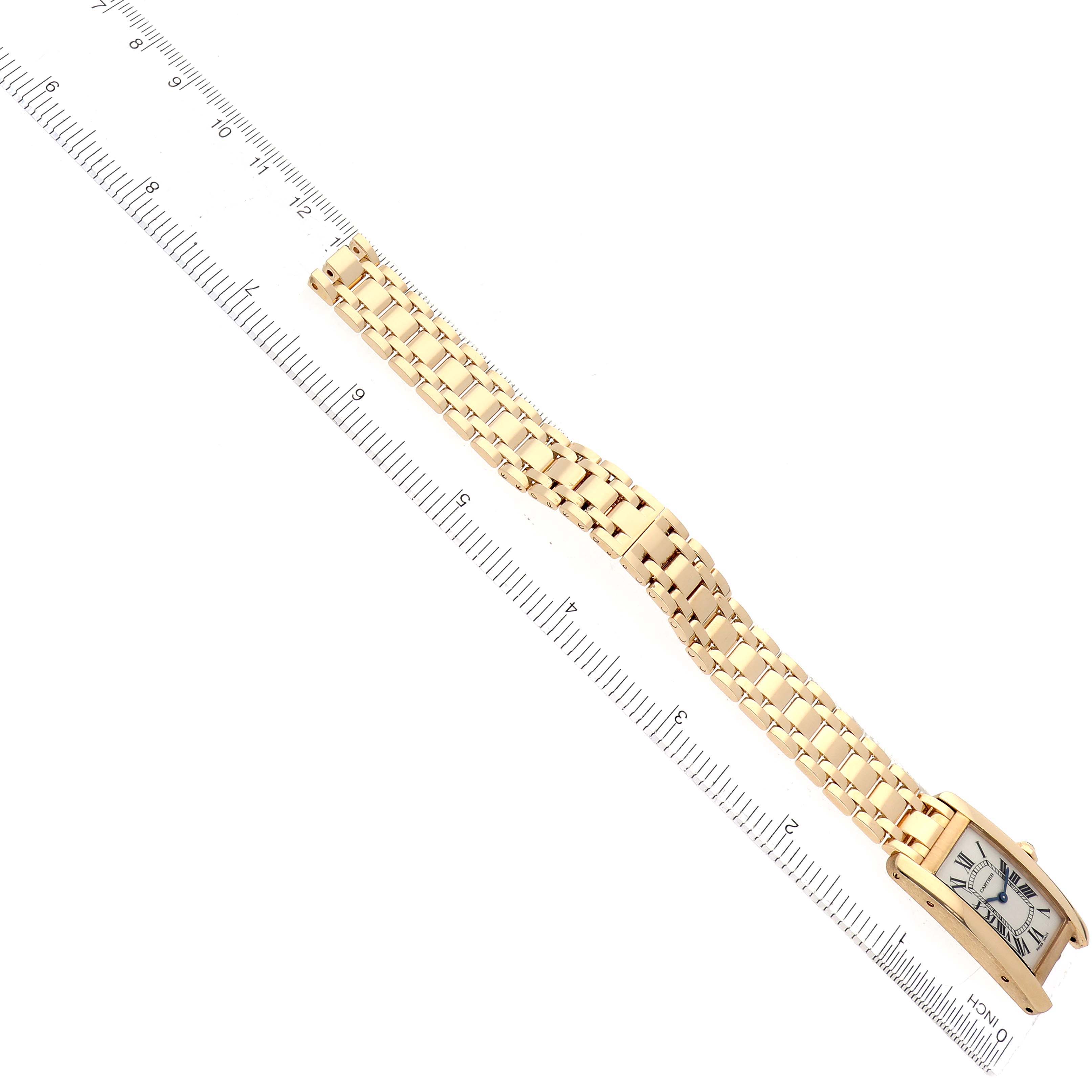 The Cartier Tank Américaine watch is shown from a diagonal top view, highlighting the face and linked metal bracelet alongside a ruler.